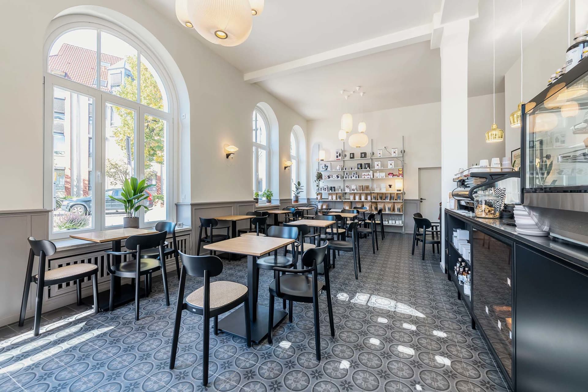 A modern cafe with multiple tables and chairs, white walls, and a bright and airy atmosphere