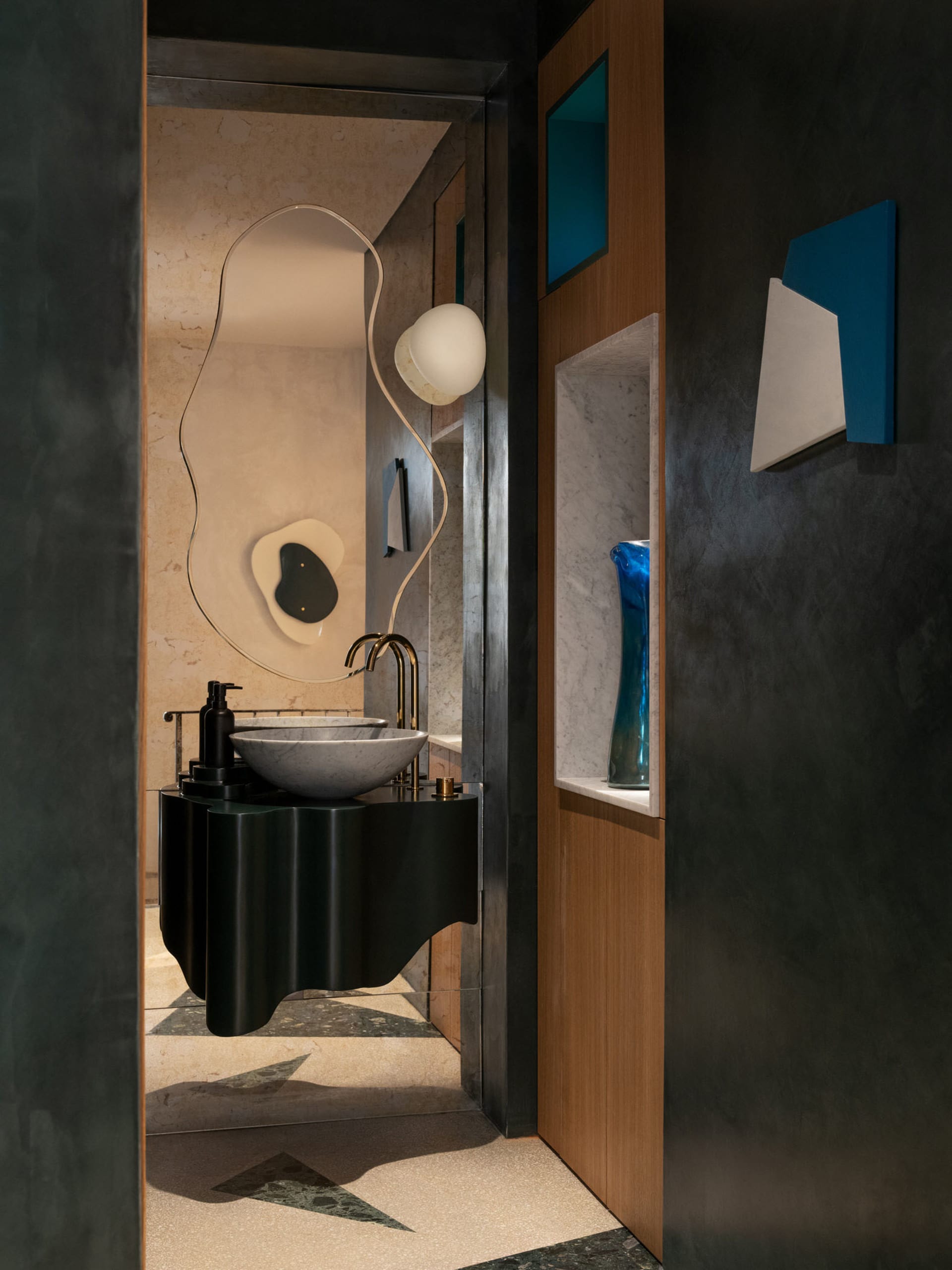 Modern bathroom with two sinks, a black countertop, a mirror, and a vase, creating a sense of depth and decoration