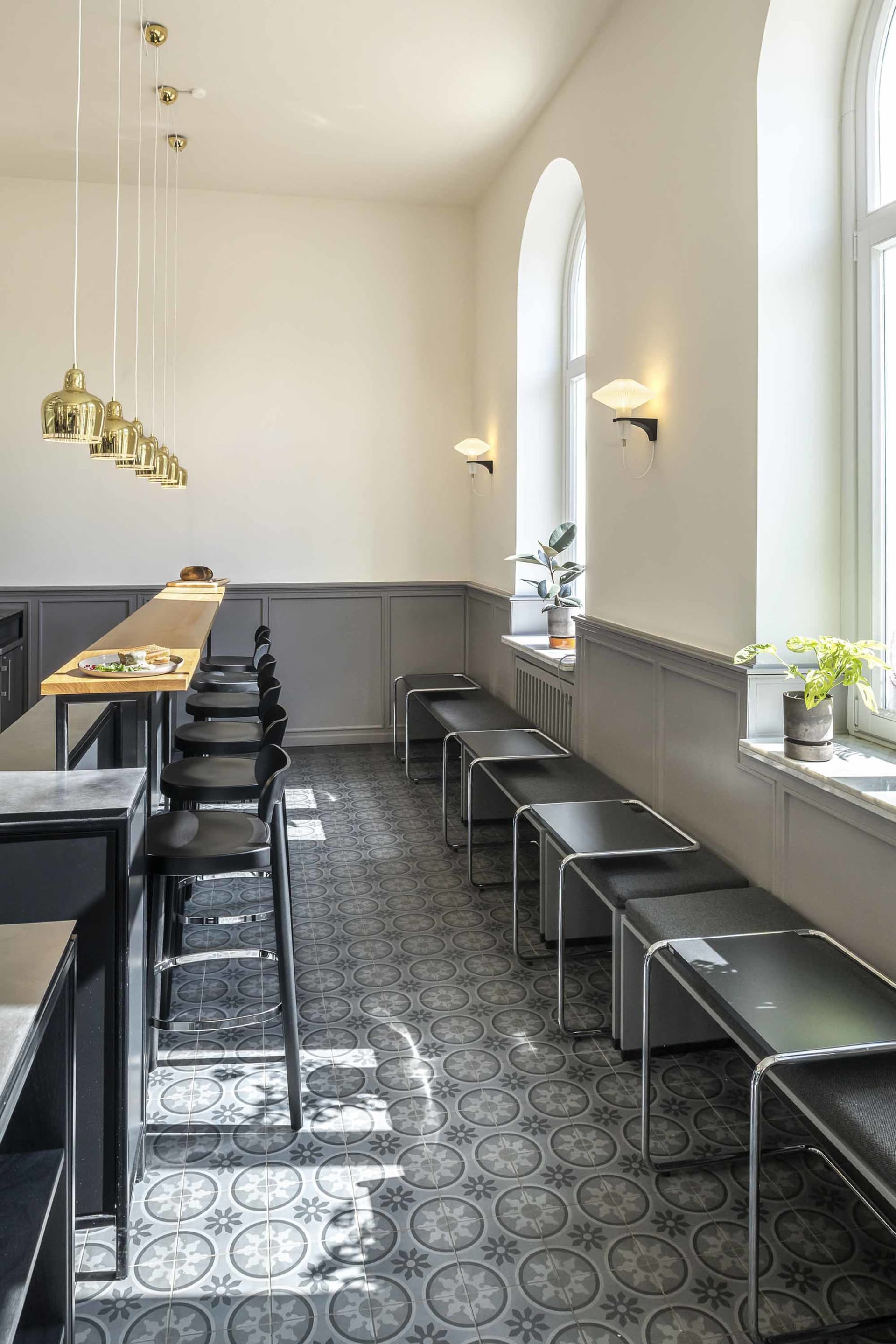 A dimly lit restaurant with a modern design, featuring a dining table and chairs, a countertop, and gray and white tones