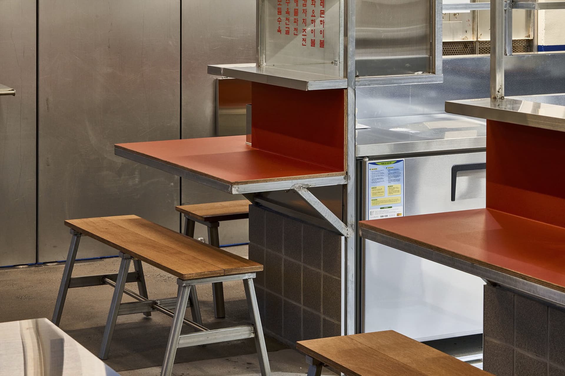 Industrial kitchen with a wooden countertop, metal stools, and two benches, featuring a functional and inviting space for food preparation and dining