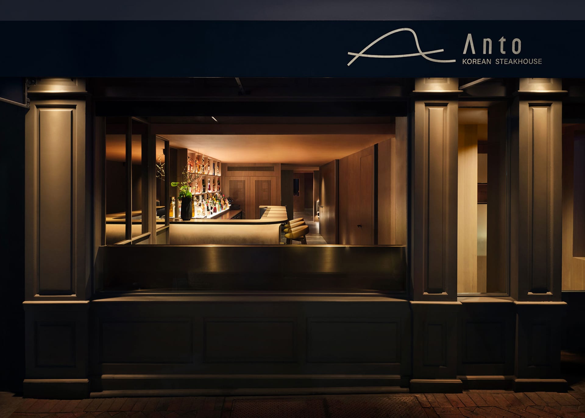 Modern Asian restaurant interior with a bar area, dining table, and comfortable seating, featuring a warm and inviting atmosphere