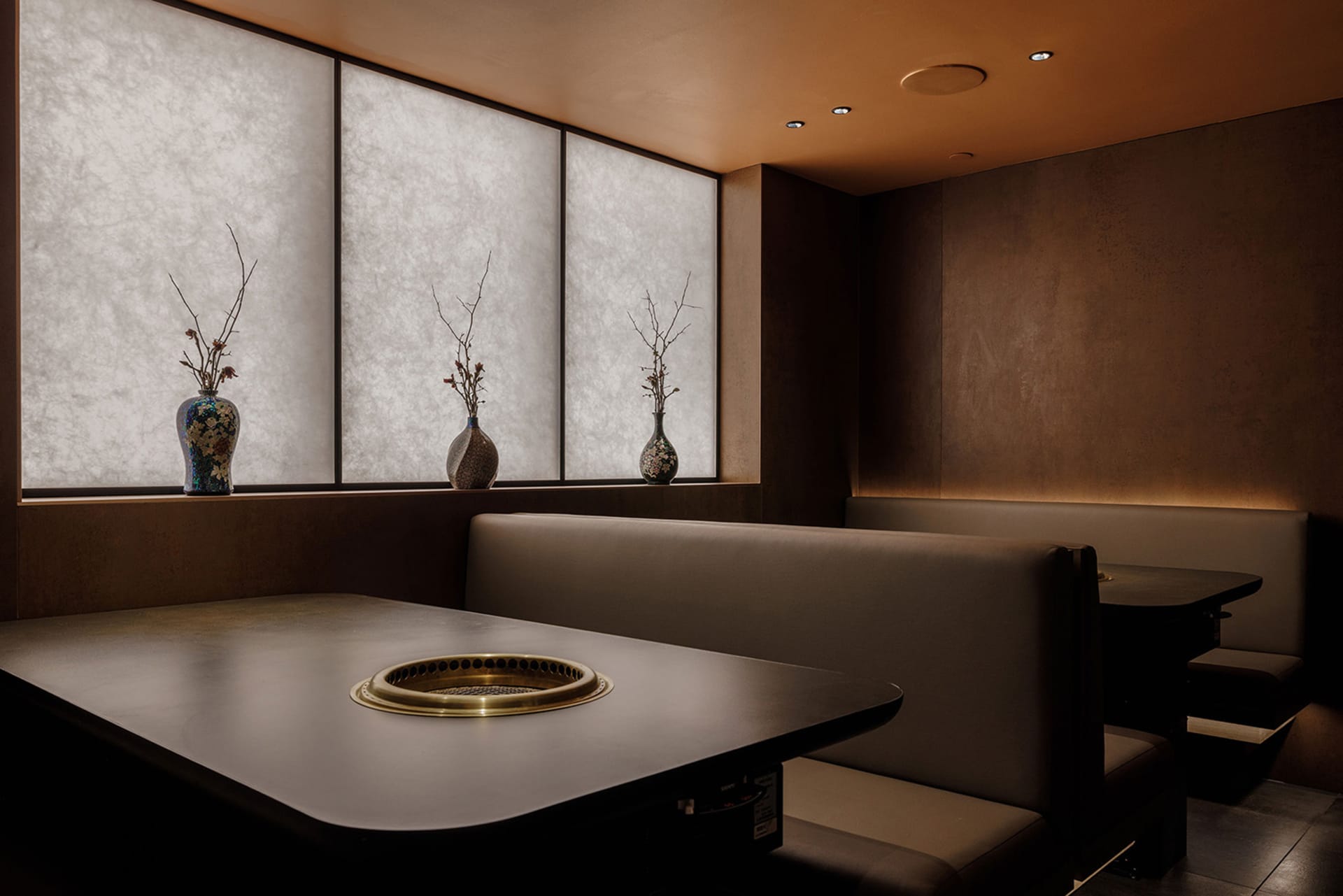A modern restaurant with a brown color scheme, featuring multiple dining tables and chairs, creating a warm and inviting atmosphere