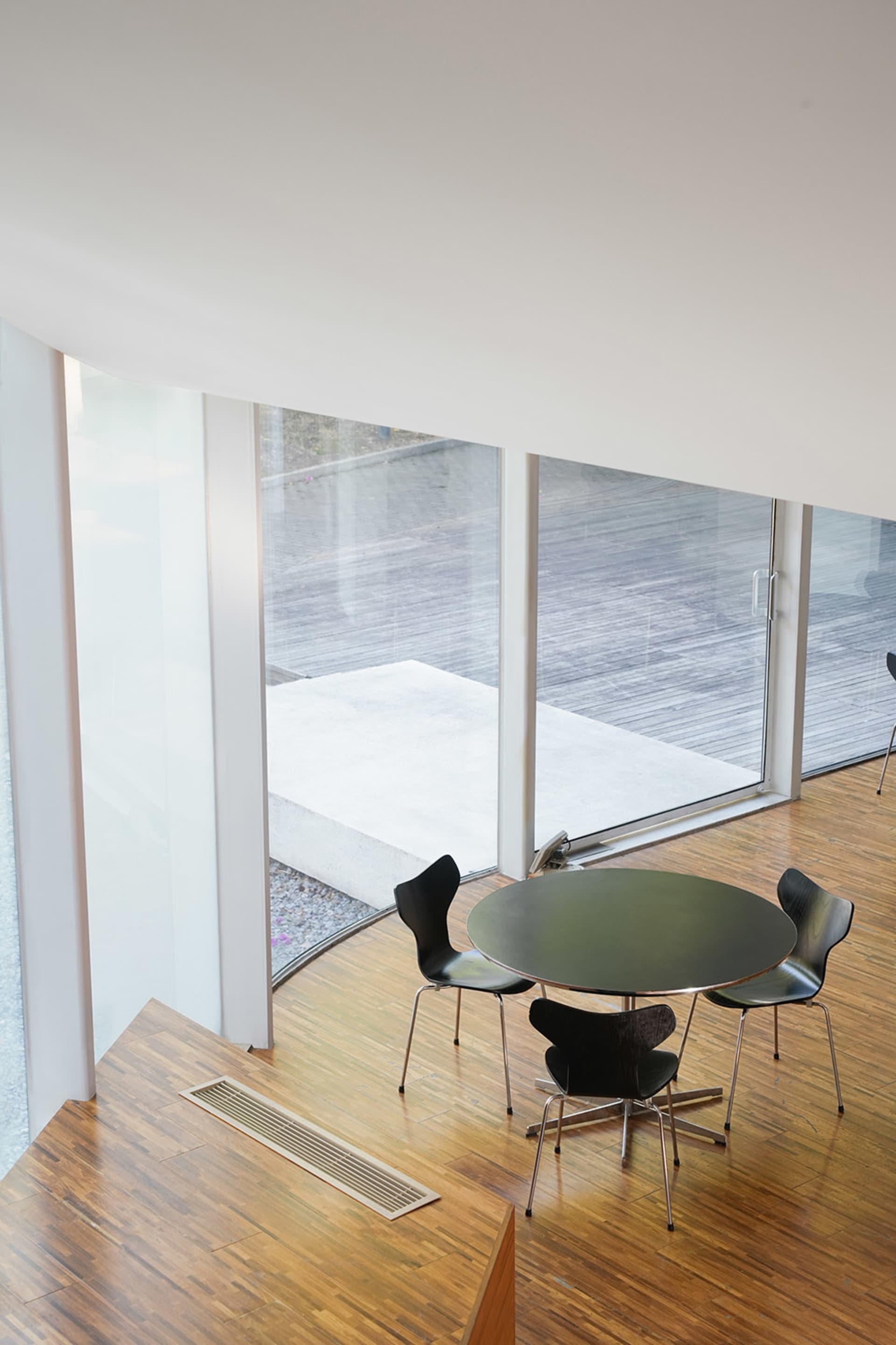 A spacious office space with a circular glass table surrounded by black chairs in a symmetrical arrangement, giving off a sleek and contemporary vibe
