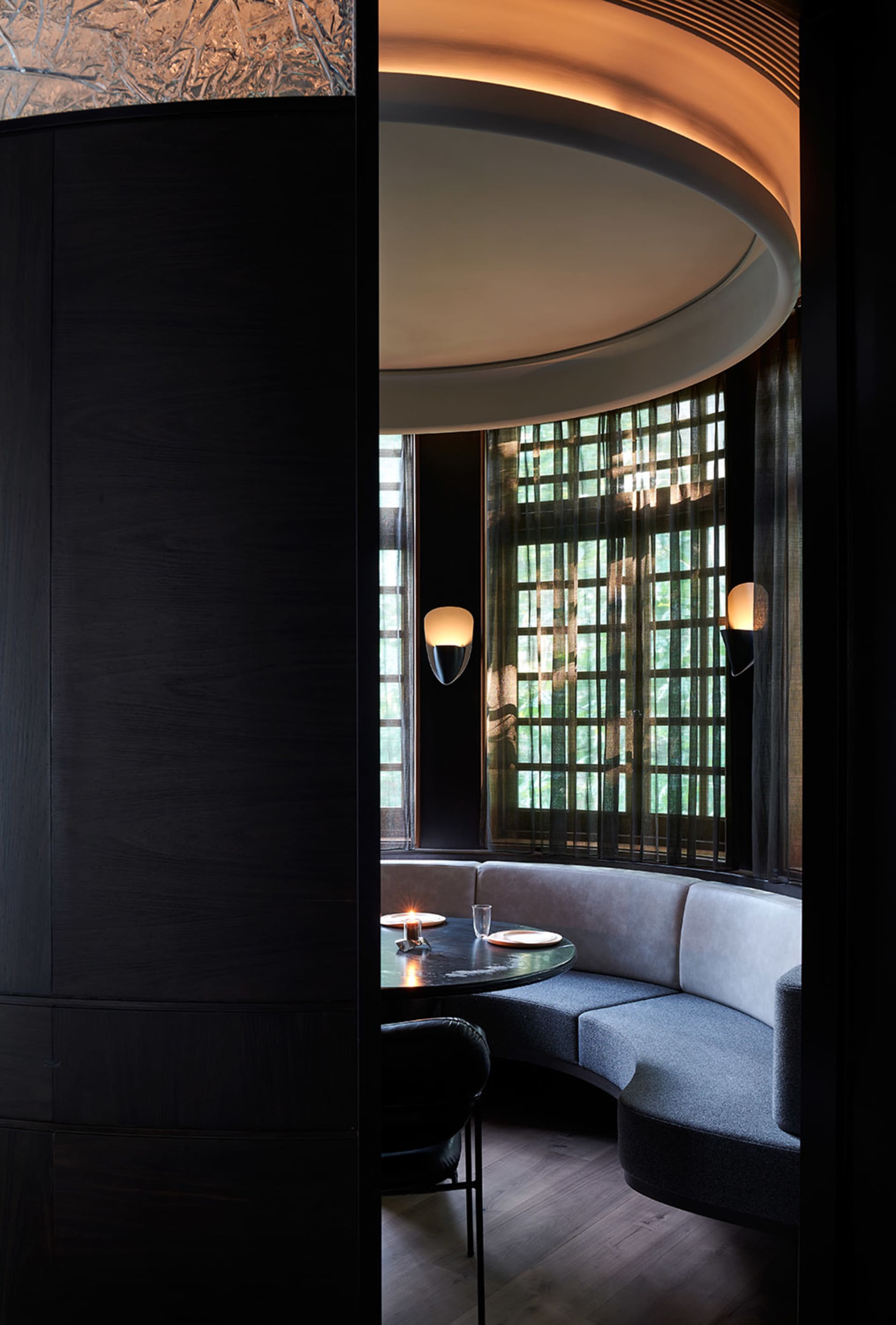 A black and white interior space with two couches, a dining table, chairs, and a large window allowing natural light