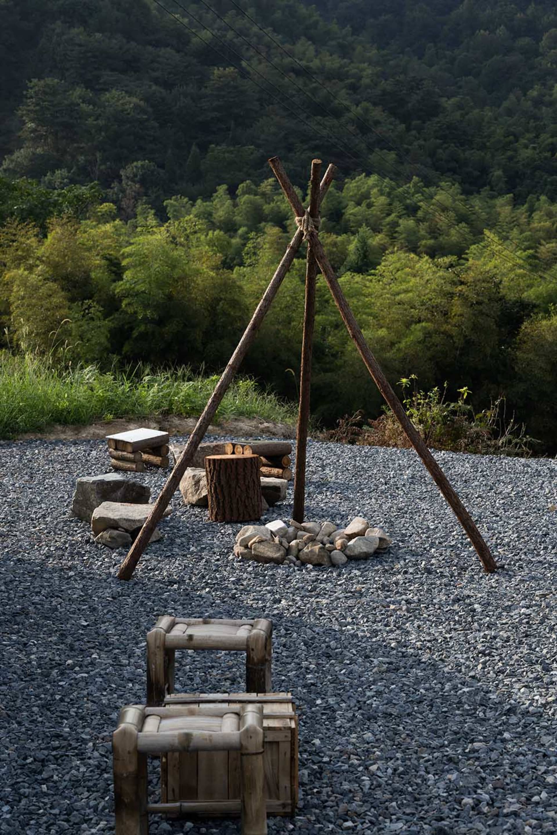 A cozy outdoor camping area with a wooden structure, fire pit, and two benches, perfect for colder months