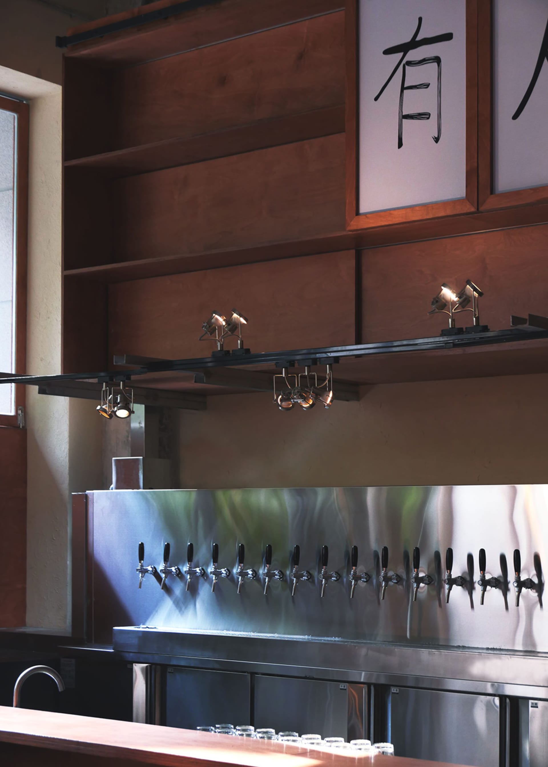A modern bar area with stainless steel fixtures and a large number of beer taps mounted on the wall in a lively social environment