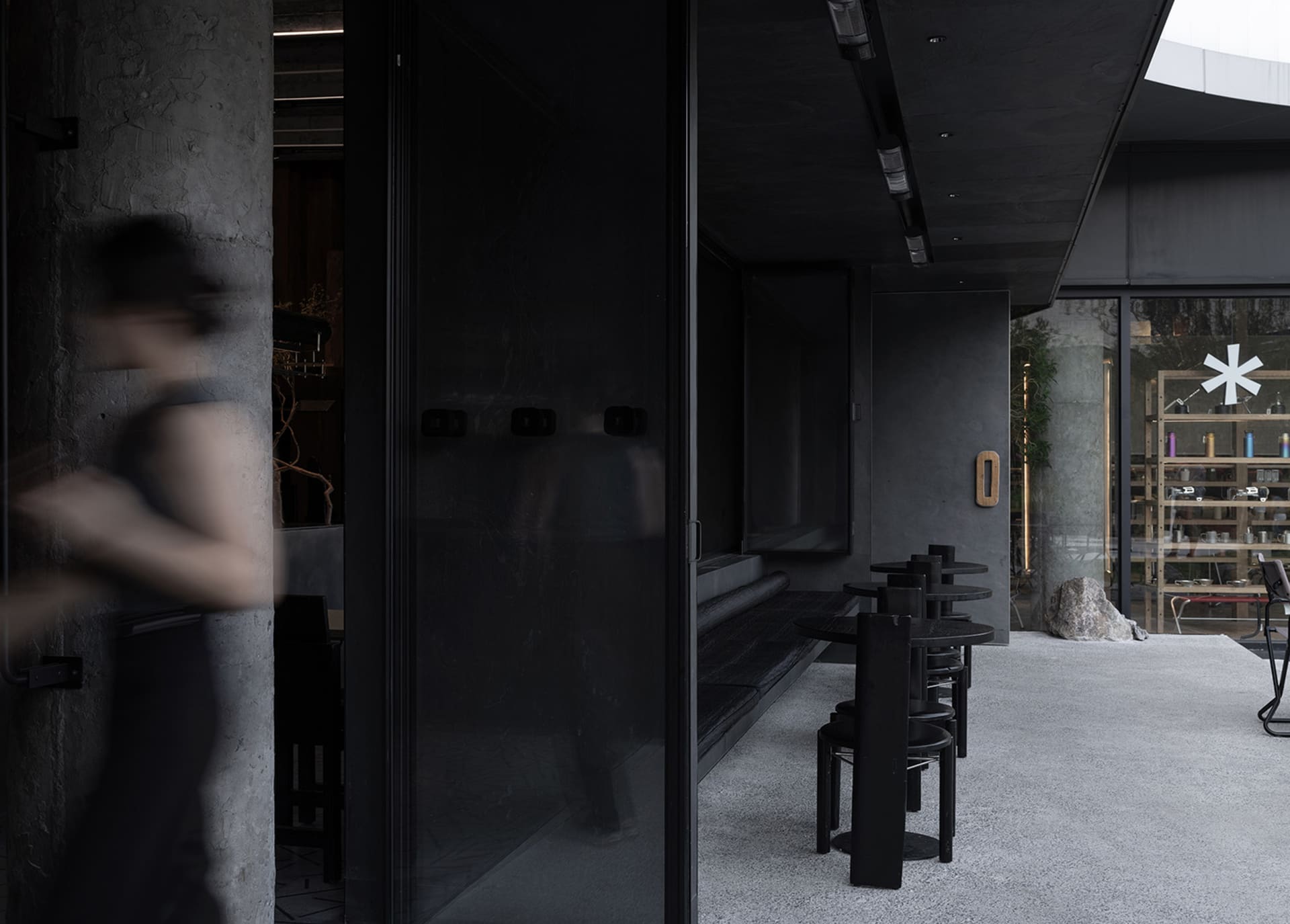 A dark restaurant interior with a black doorway, chairs, and a mysterious atmosphere