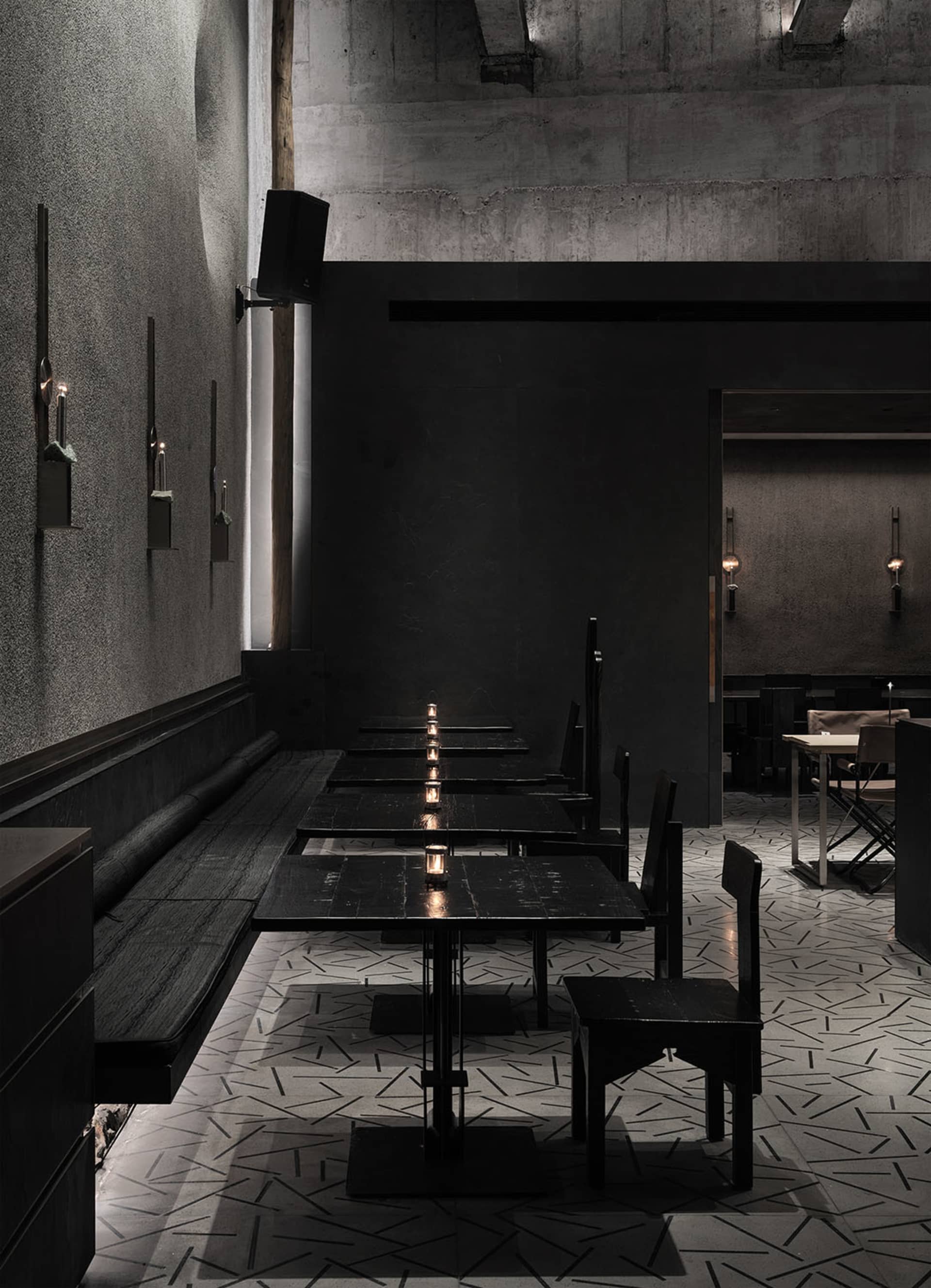 Empty modern restaurant with black walls, dining tables, and candles creating a warm atmosphere