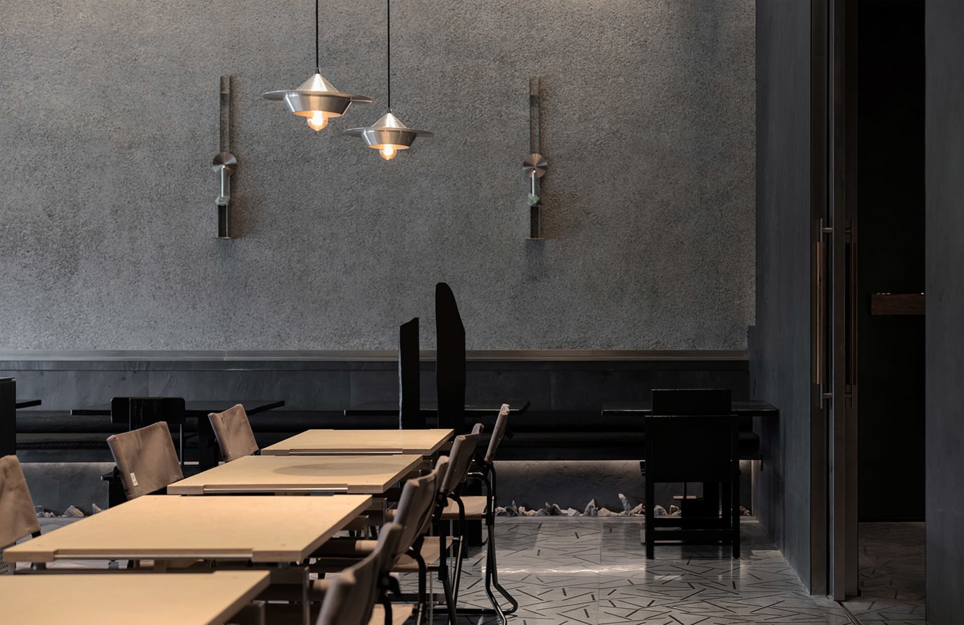 A modern restaurant with several dining tables and chairs, featuring a clean and well-organized atmosphere with soft and warm lighting