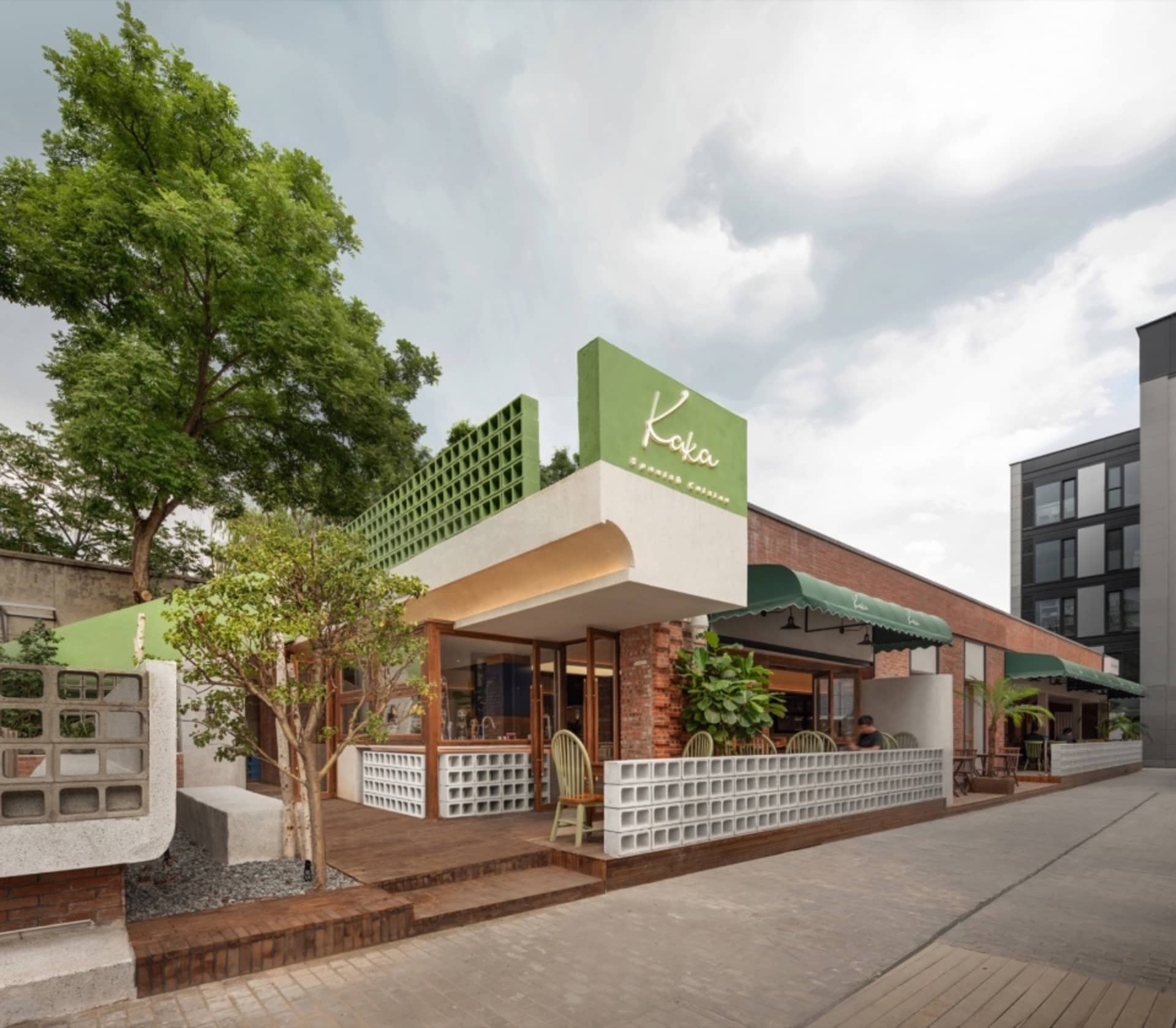 An inviting outdoor restaurant patio with green awnings, chairs, and dining tables under umbrellas
