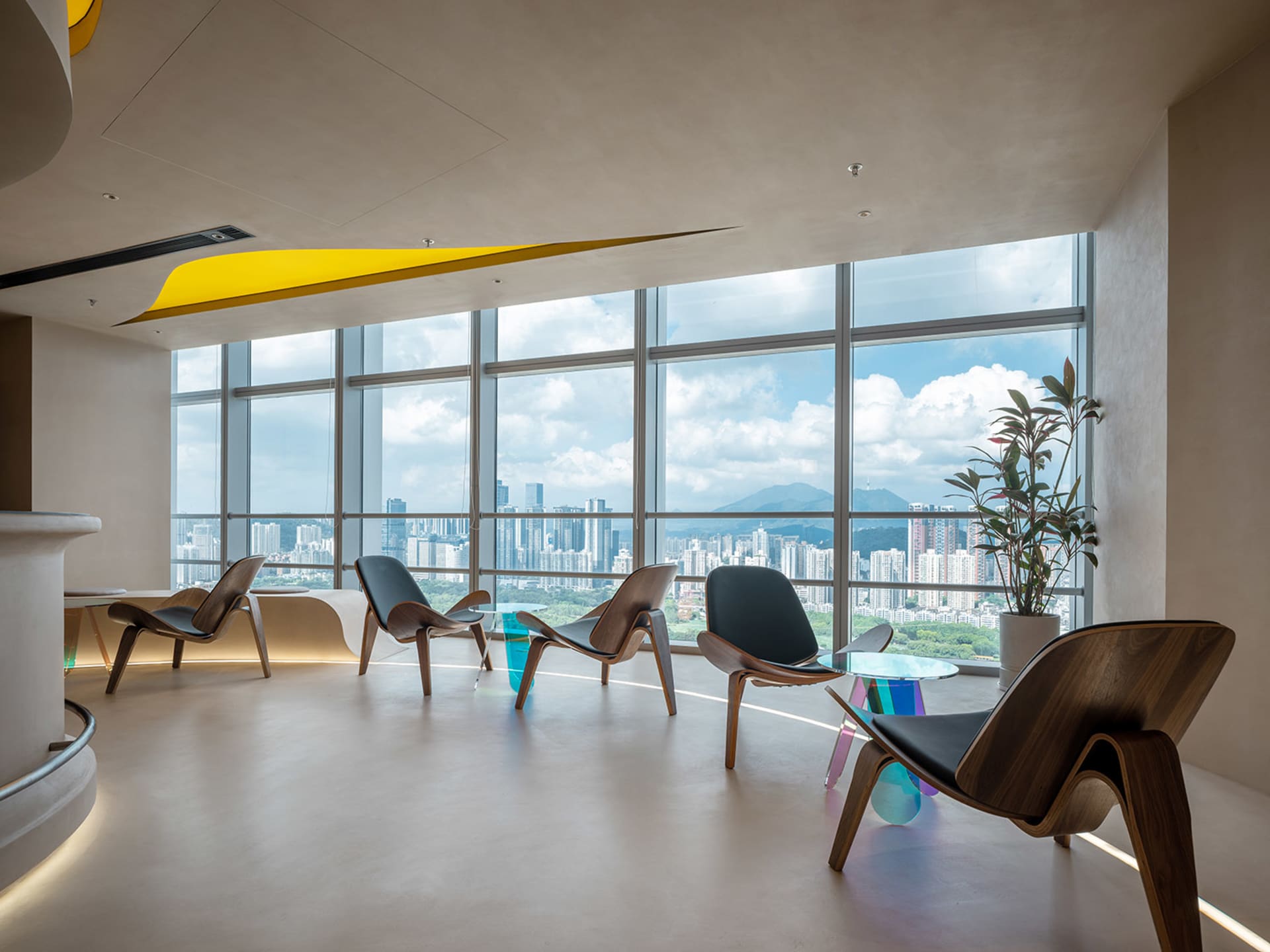 Open modern living area with a large window offering a city view, featuring unique chairs, including one resembling a boat, amidst a comfortable and inviting atmosphere