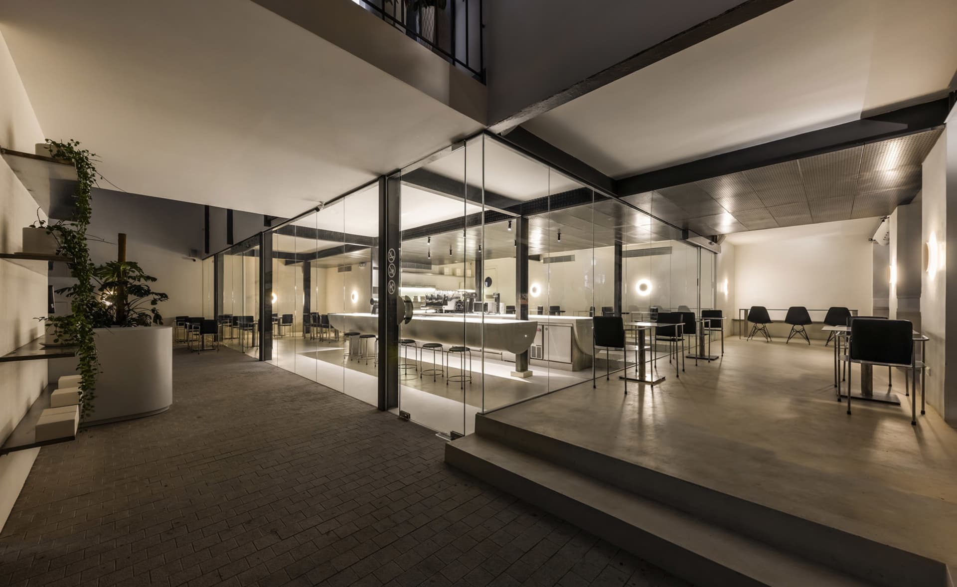 A lively modern restaurant interior with a large dining area, brick and concrete flooring, and multiple tables and chairs