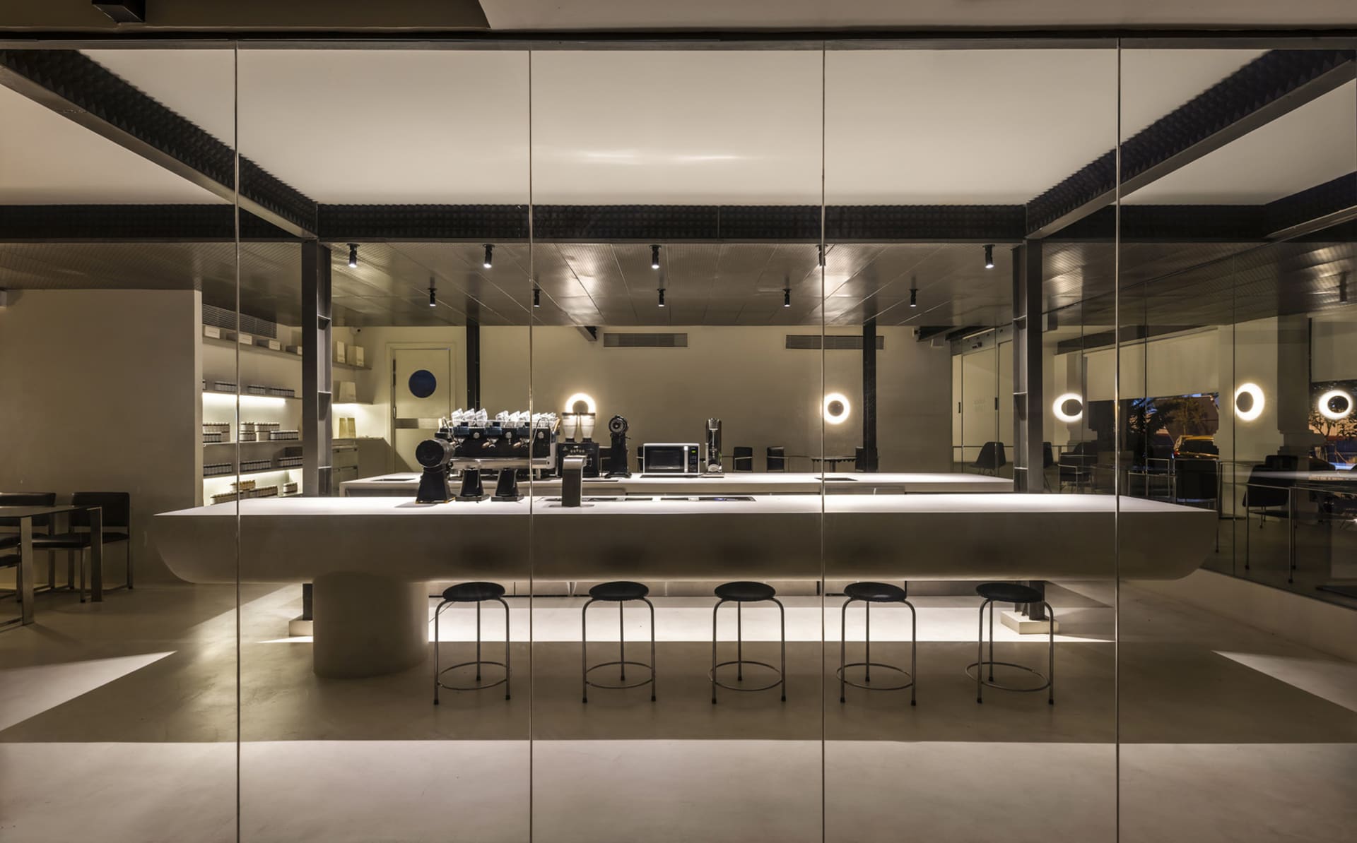 Industrial kitchen with a long countertop featuring stools, cups, and a laptop, in a clean and organized restaurant setting