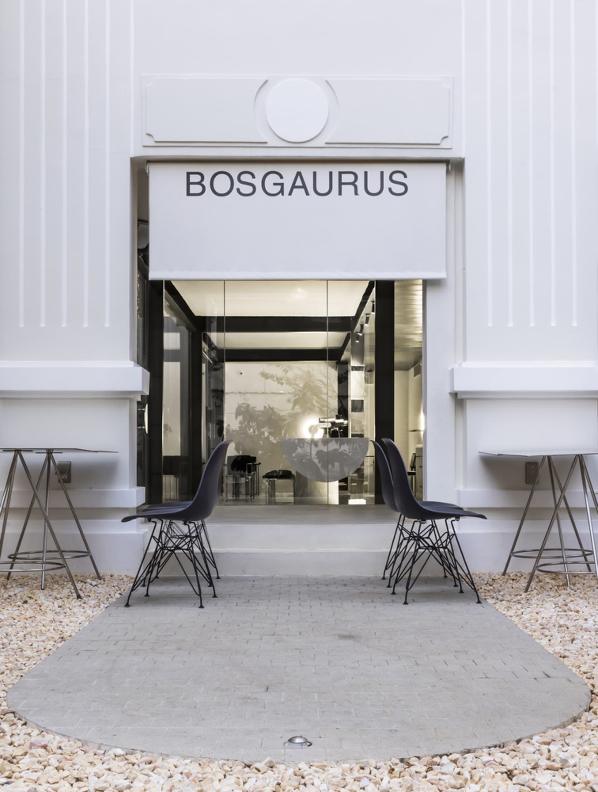 A modern storefront display featuring chairs and tables, with a clean and bright appearance, likely made of white materials