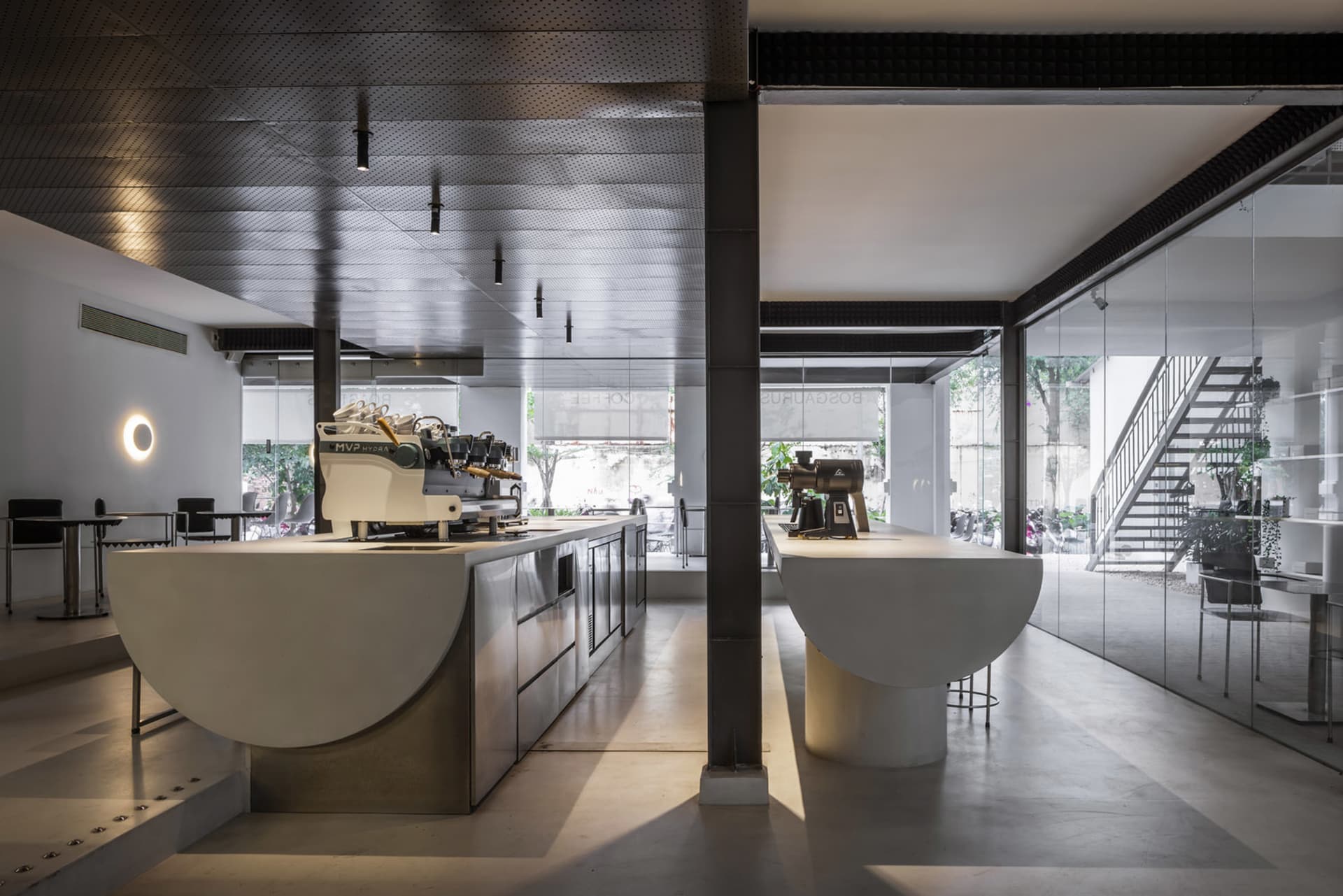 Industrial kitchen with two white sinks, two coffee makers, and three chairs, featuring a clean and organized atmosphere with a focus on functionality and efficiency