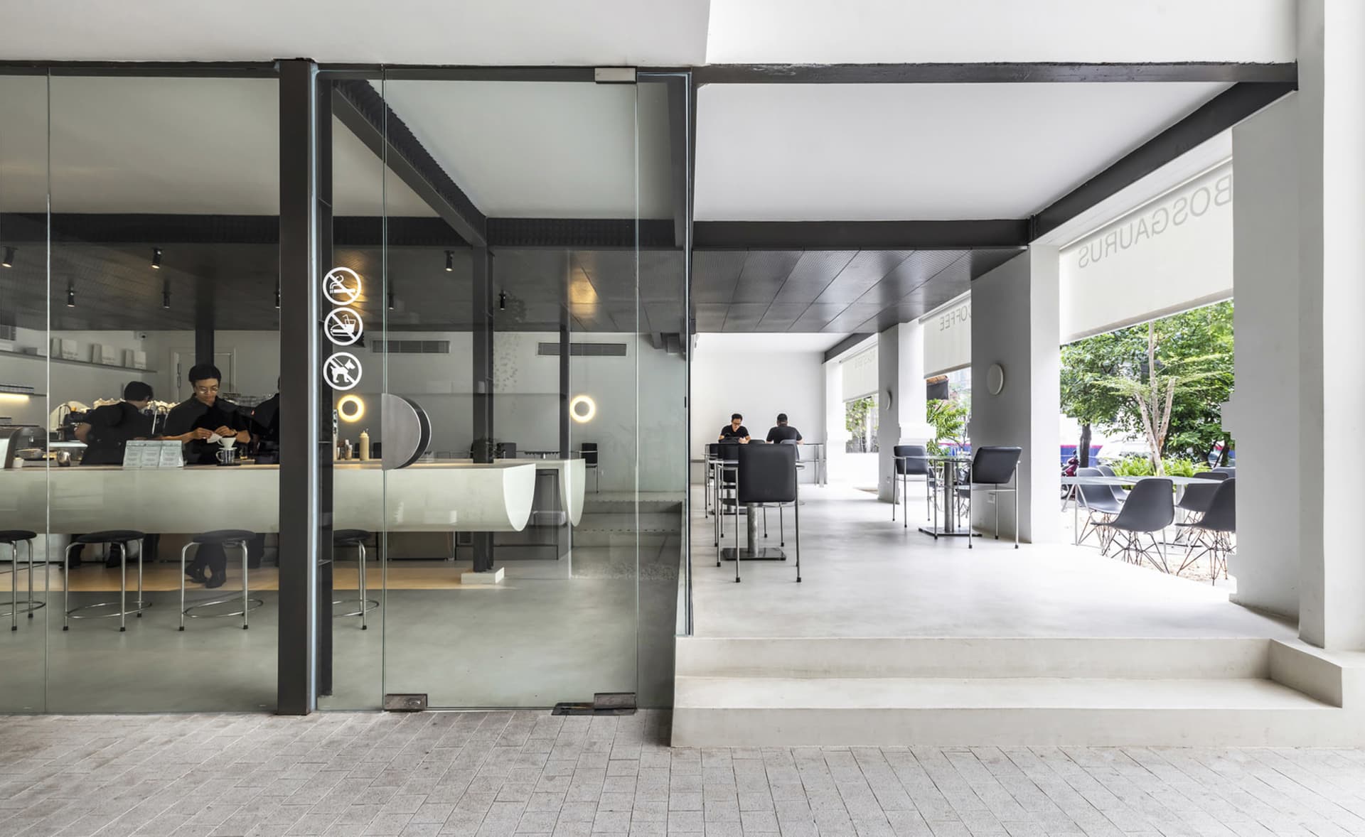 A modern cafe interior with a glass door, chairs, a dining table, and clocks, set in a spacious area with ample seating options
