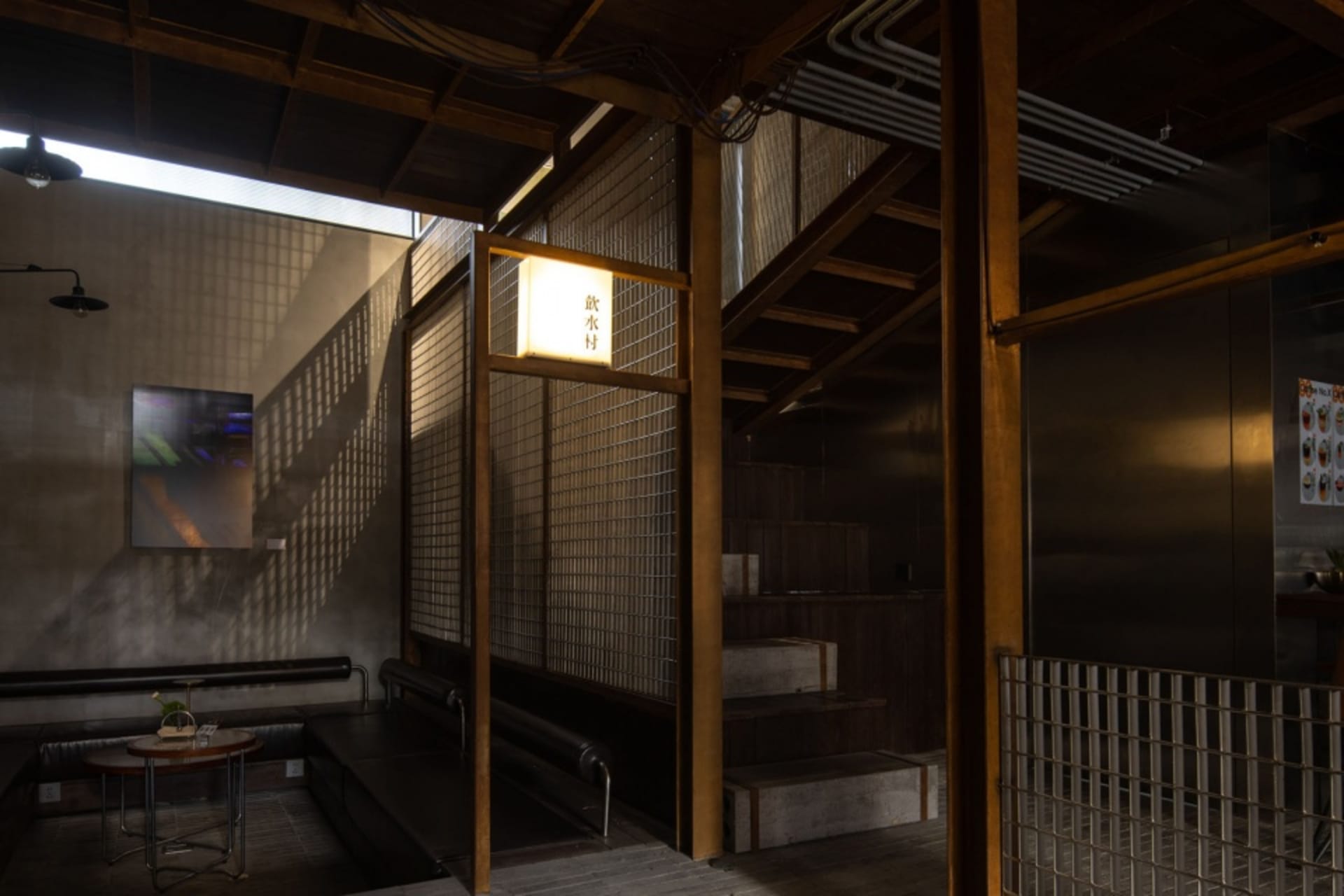 Modern stairwell with wooden stairs, metal railing, and a bench, giving off a sleek and modern vibe