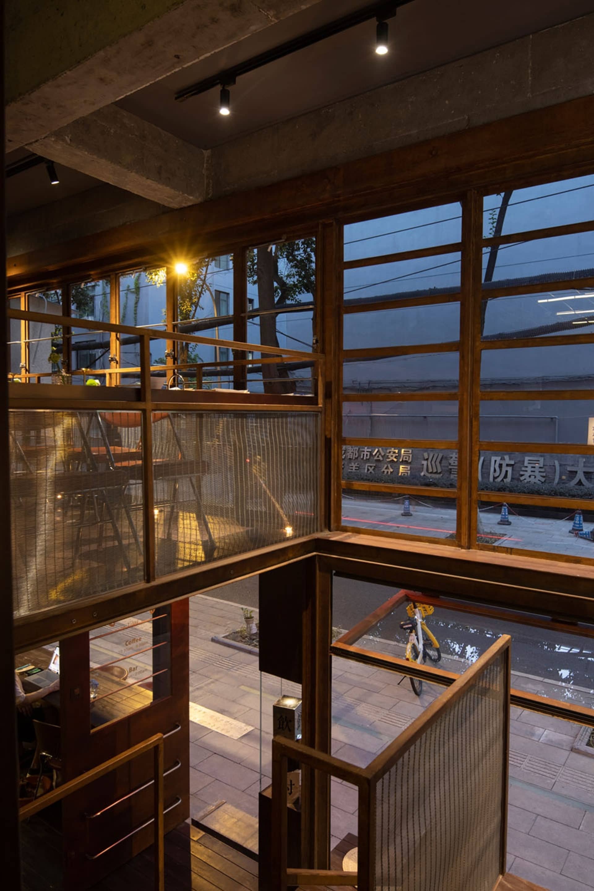 A modern interior space with a staircase, wood, and glass elements, featuring natural light and a sense of elegance