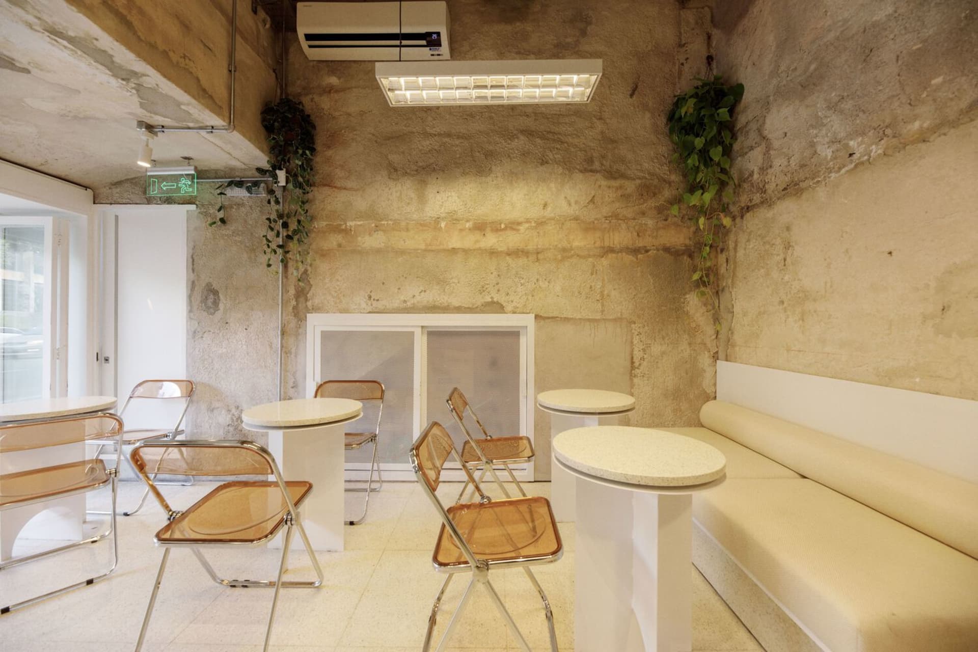 Modern cafe interior with stone walls, a white bench, and chairs placed around a dining table and scattered throughout the space