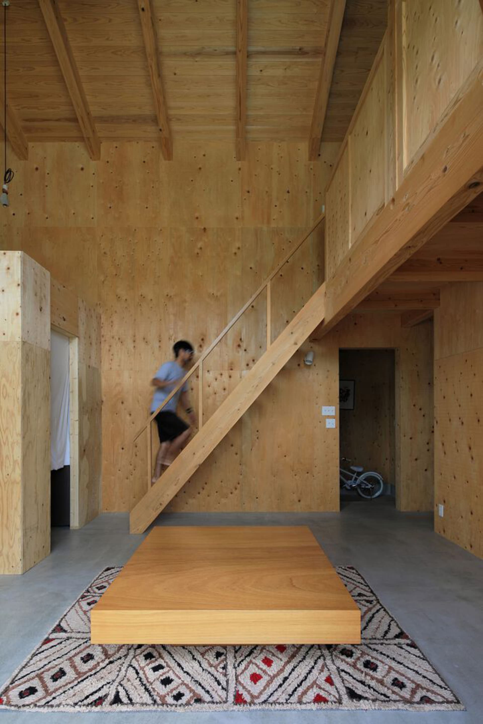 A wooden staircase in a home with a calm and serene atmosphere, featuring a man standing on the bottom step