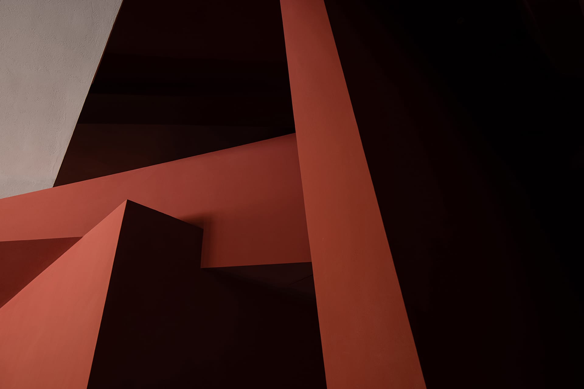 A modern staircase in a red room with a warm and inviting atmosphere, possibly featuring concrete or wood materials