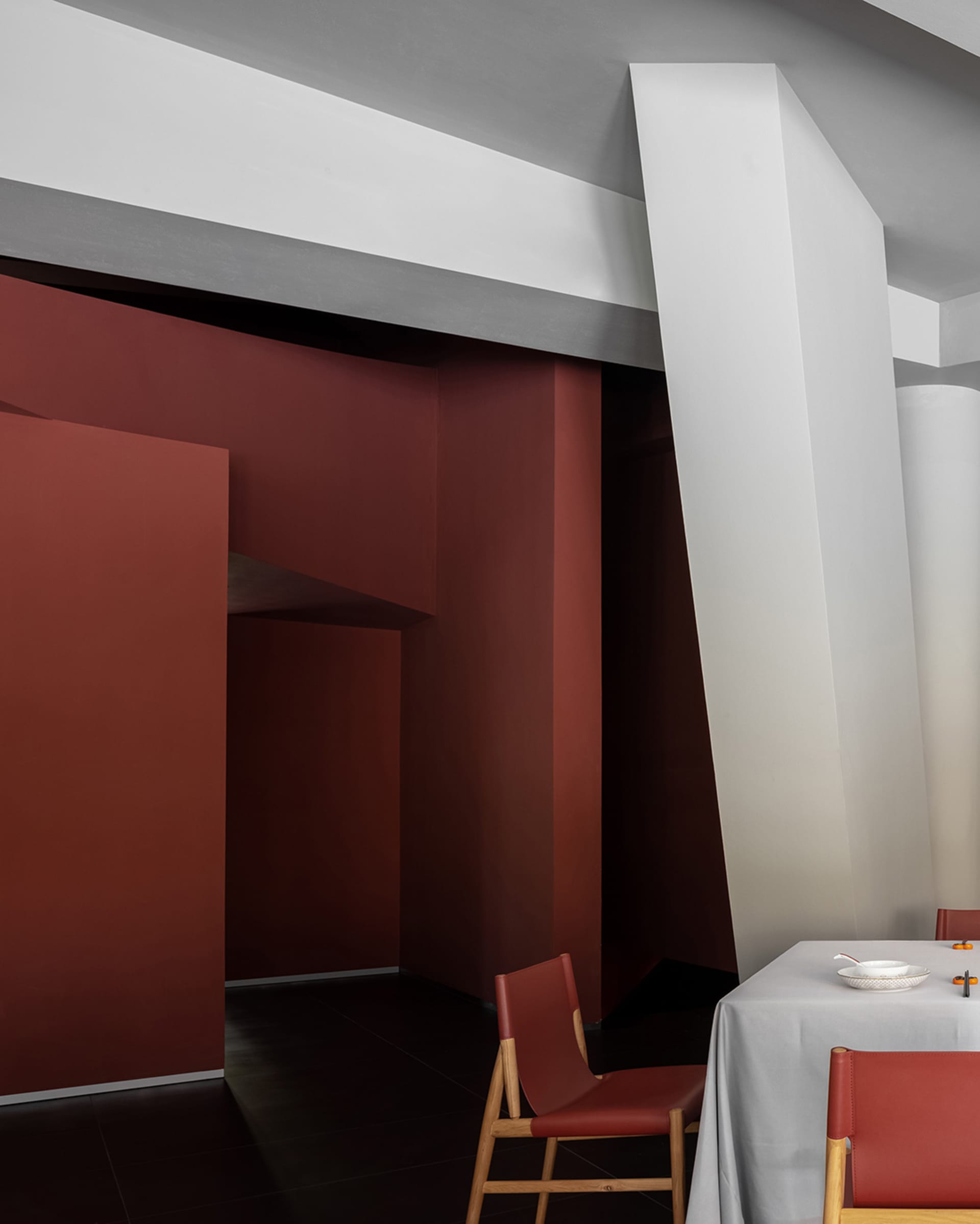 A modern dining area with two chairs and a table, surrounded by red walls and a warm ambiance