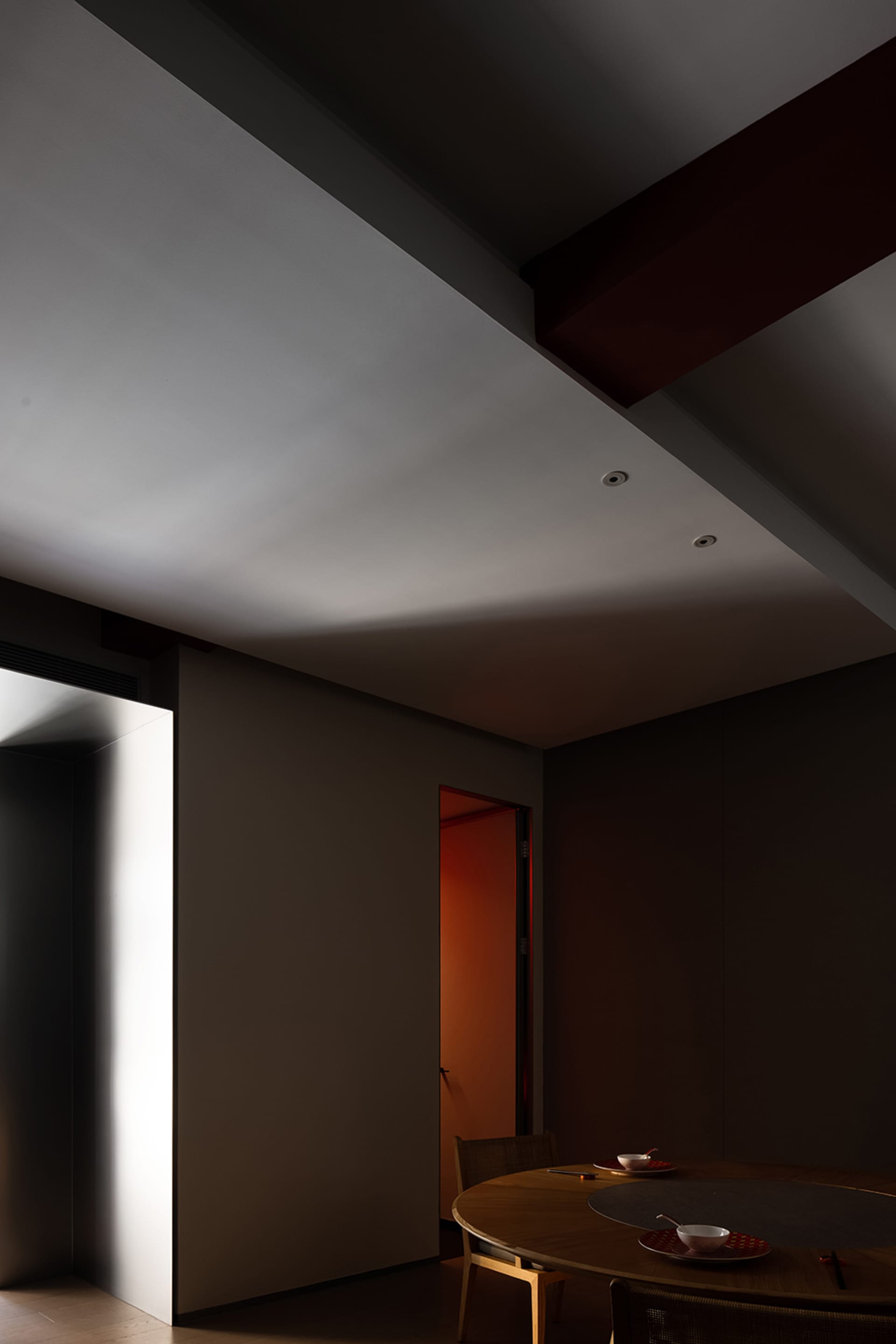 A dimly lit hallway with a gray wall and a doorway leading to another room