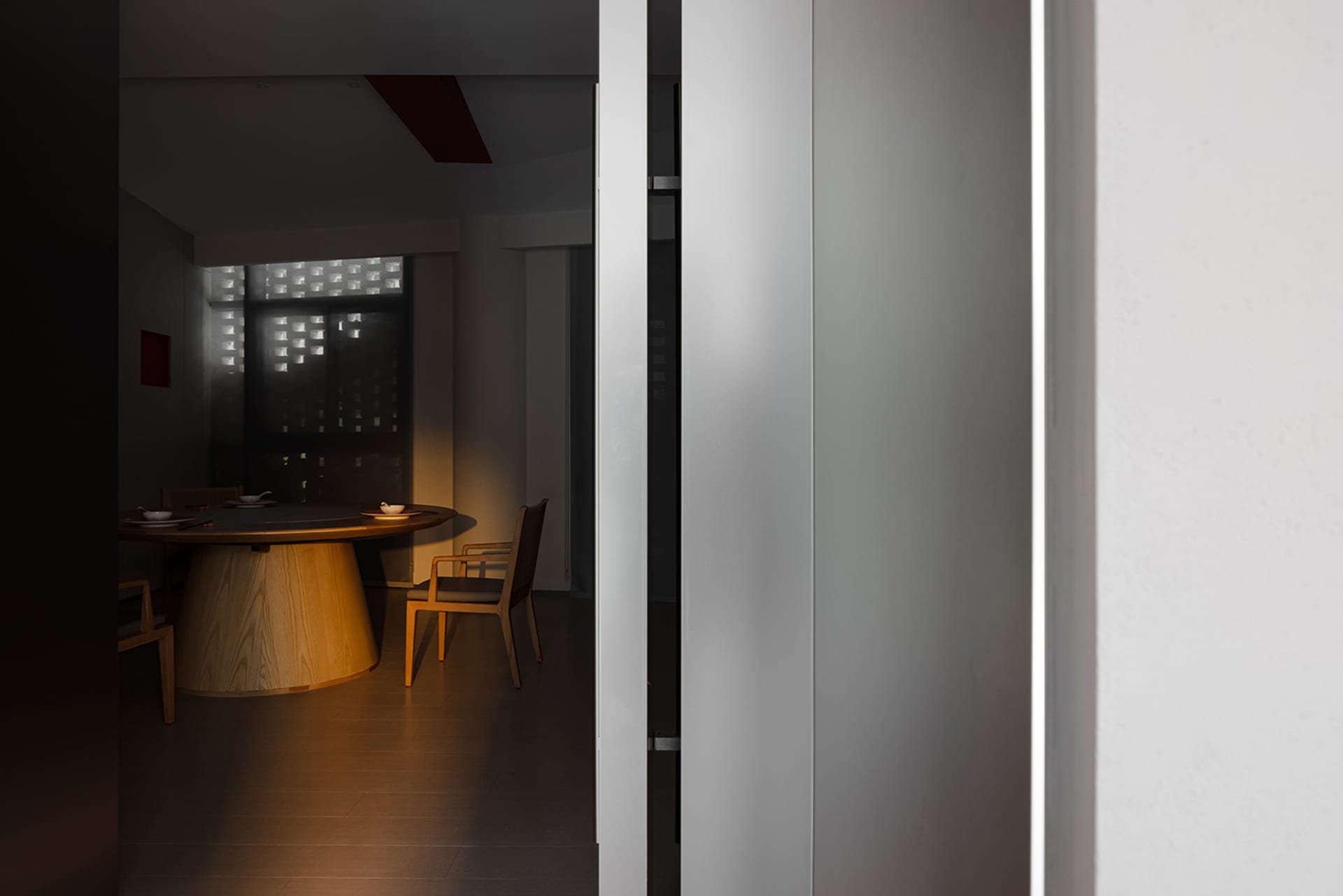 Dimly lit dining room with a wooden table and chairs, featuring red accent walls and a cozy atmosphere