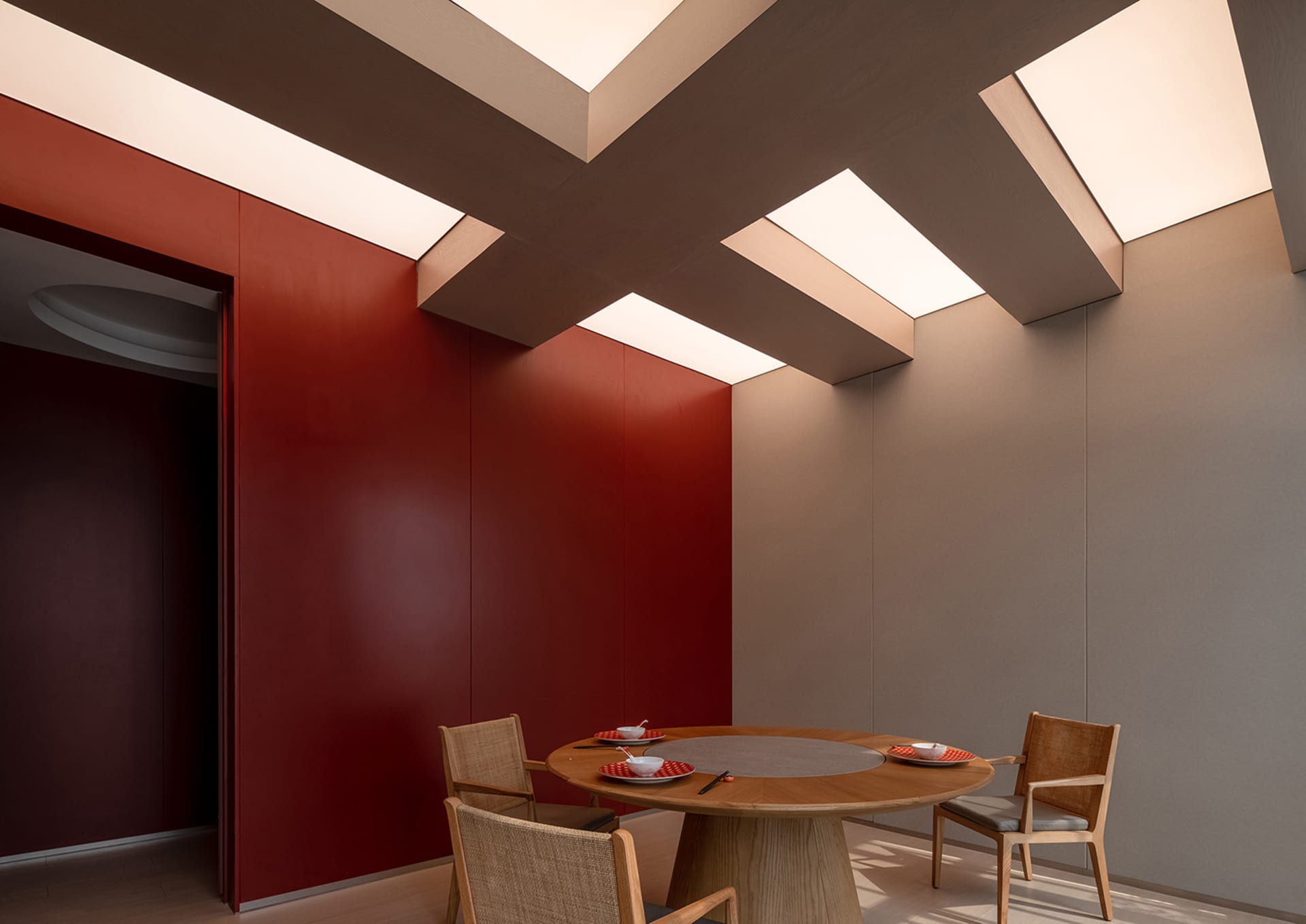 A cozy dining area with a wooden table, two chairs, plates, and cups, surrounded by red-painted walls