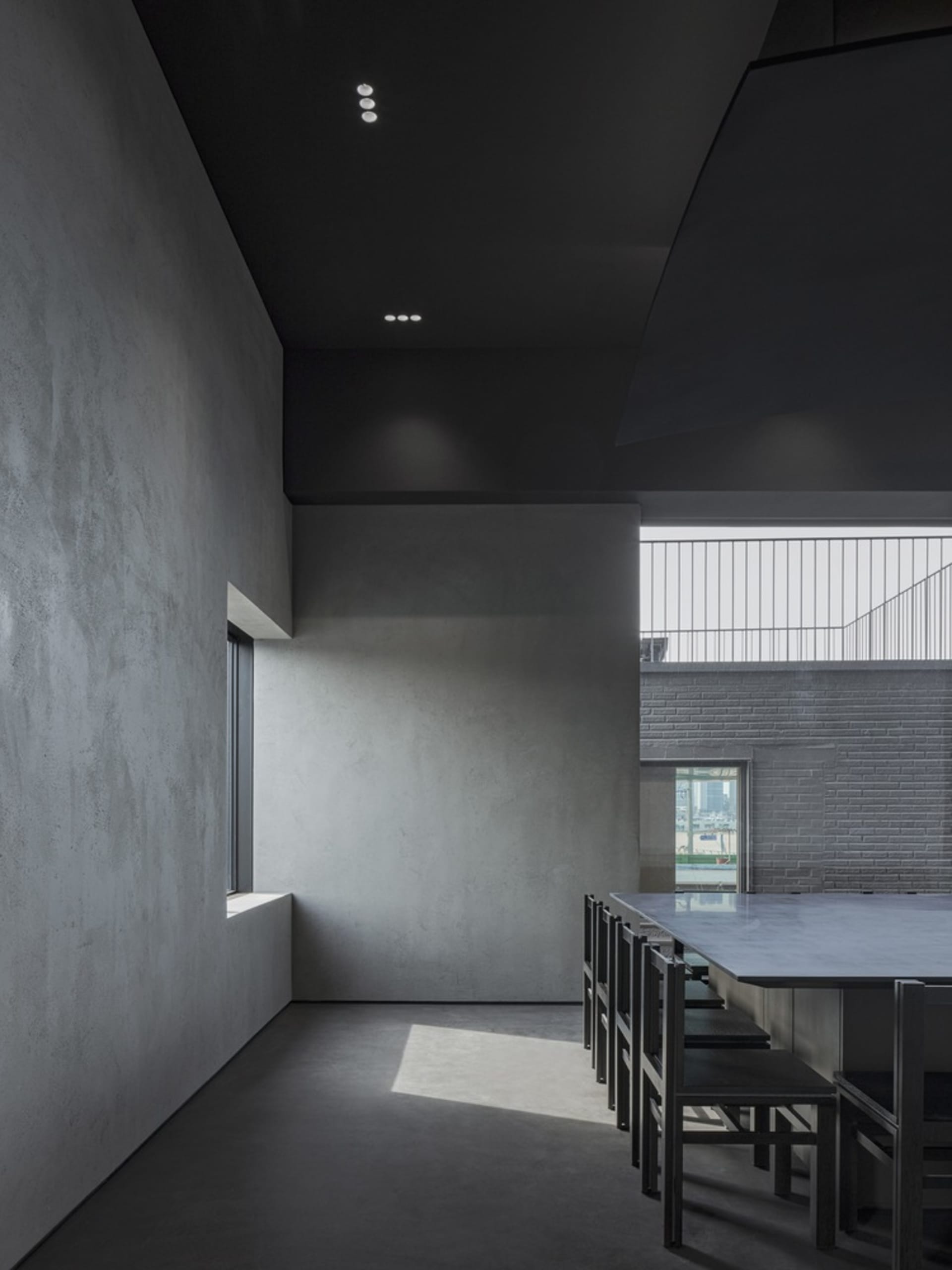 Empty room with a concrete wall, a window, and several chairs placed around the space