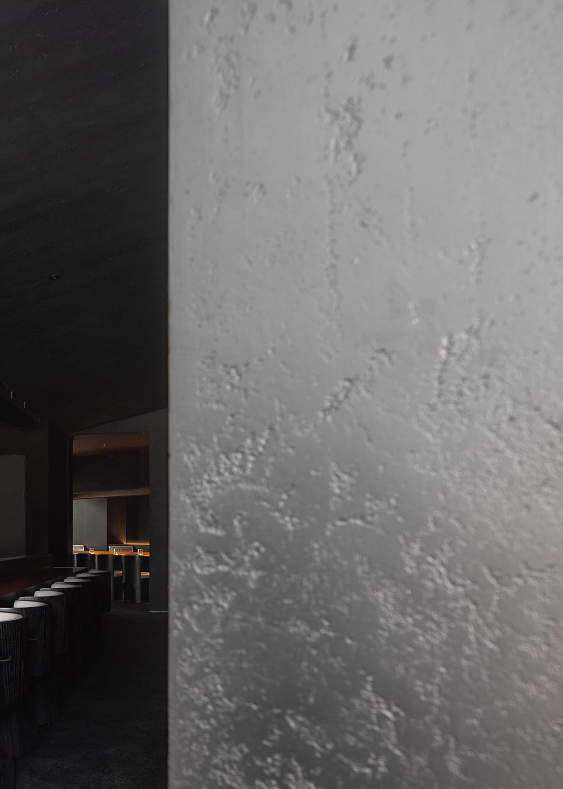 Empty dark room with a concrete wall and several chairs, giving a moody atmosphere