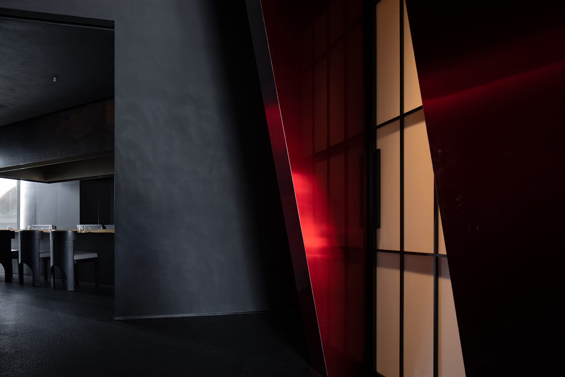Modern interior design with a bold red accent wall and a black doorway, creating a stylish contrast