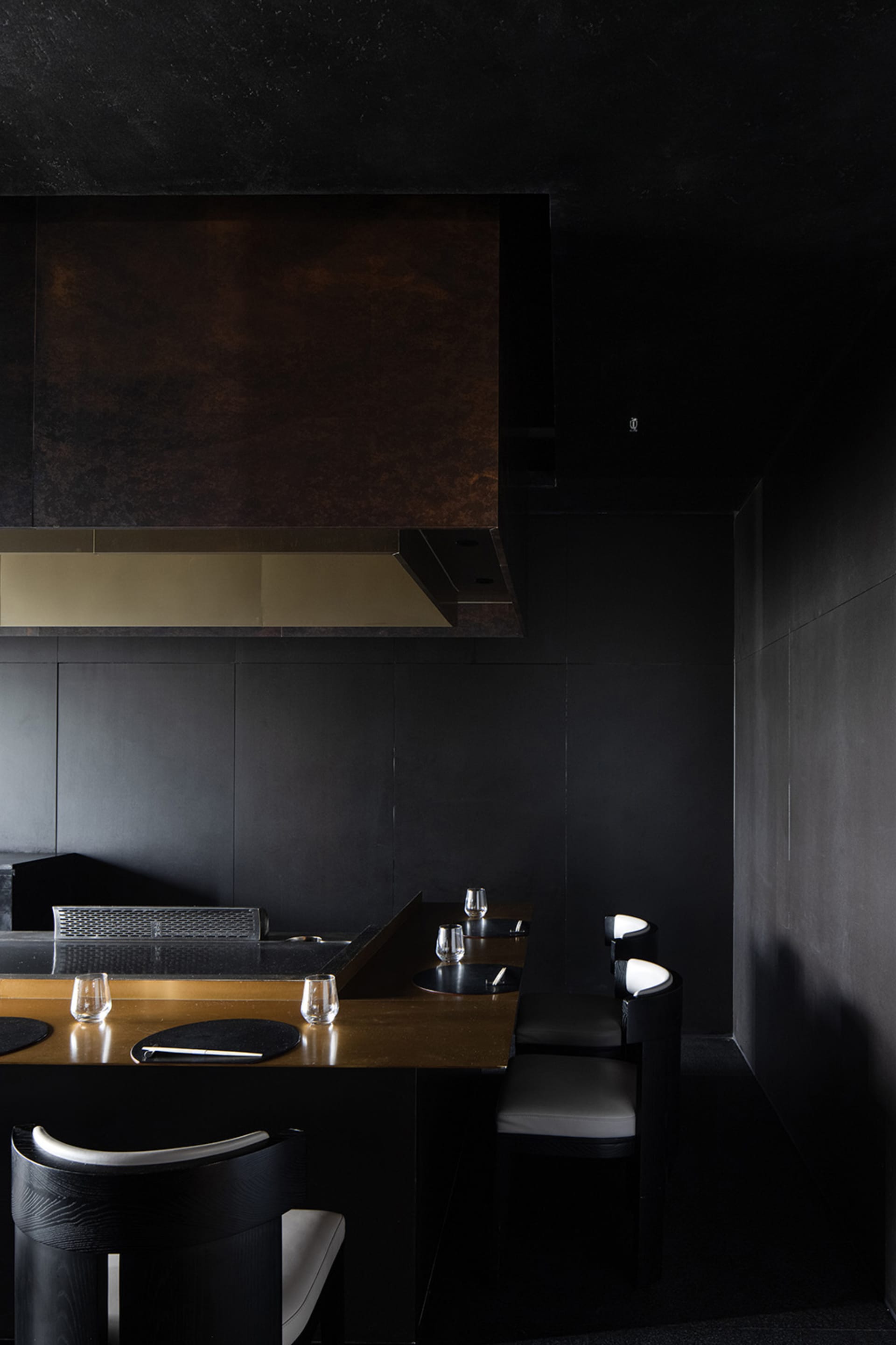 Modern kitchen with black walls, a countertop with wine glasses and knives, and a focus on functionality