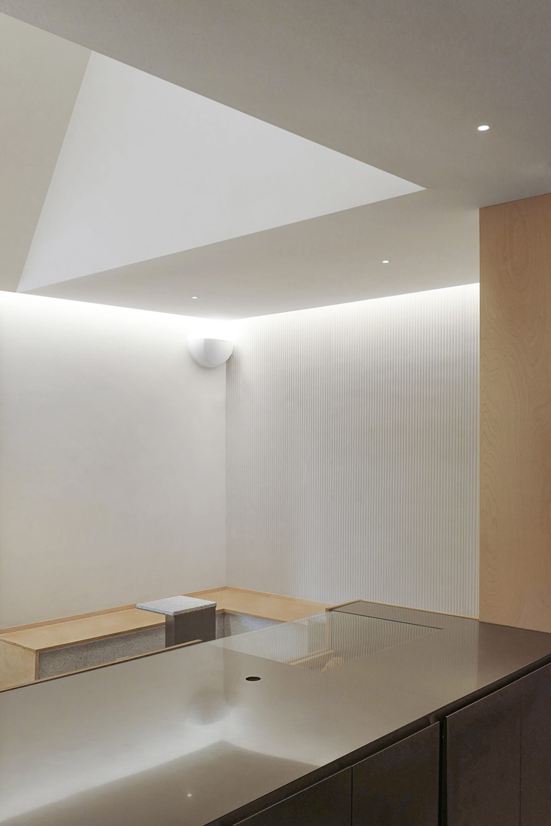 Empty minimalist kitchen with white walls, a wooden countertop, and two benches on either side