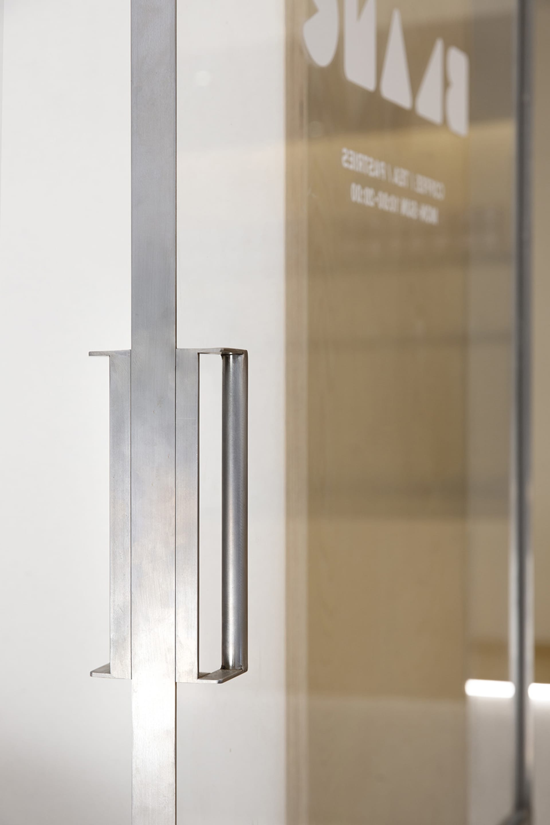 A modern interior space with a steel artwork mounted on a wall in front of a glass door, creating a sense of transparency and openness