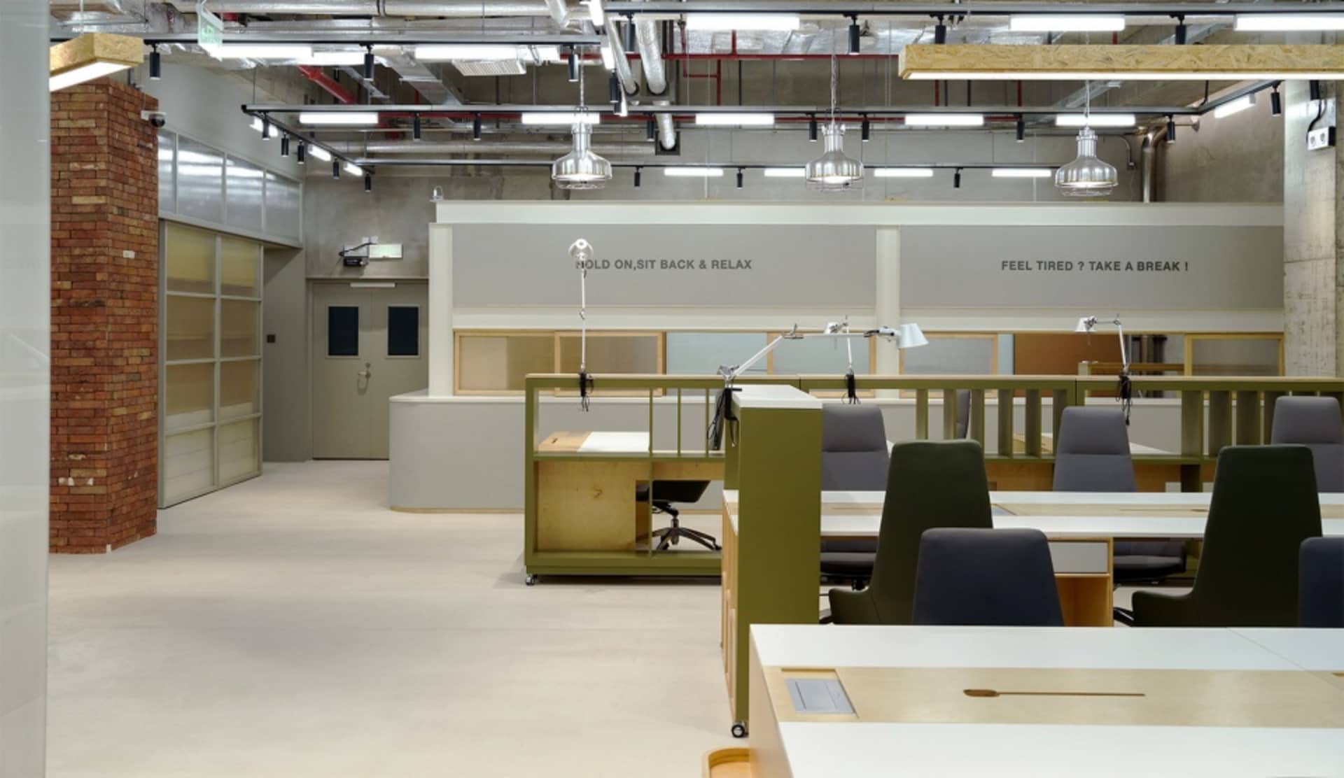 Office space with multiple workstations, including desks and chairs, and dining tables for collaboration and productivity