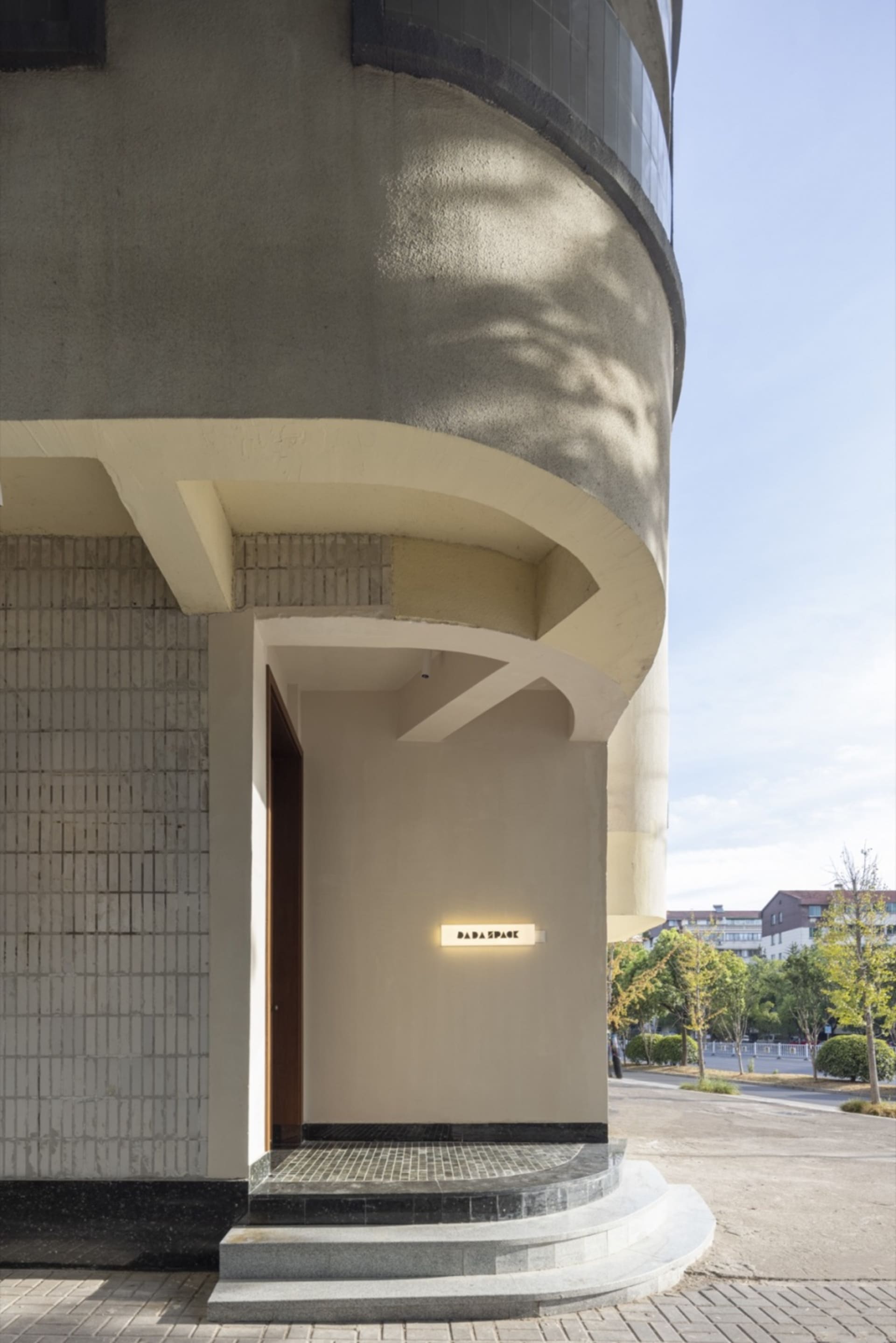 A modern building with a curved concrete wall and glass elements, featuring two doors and an open, spacious atmosphere