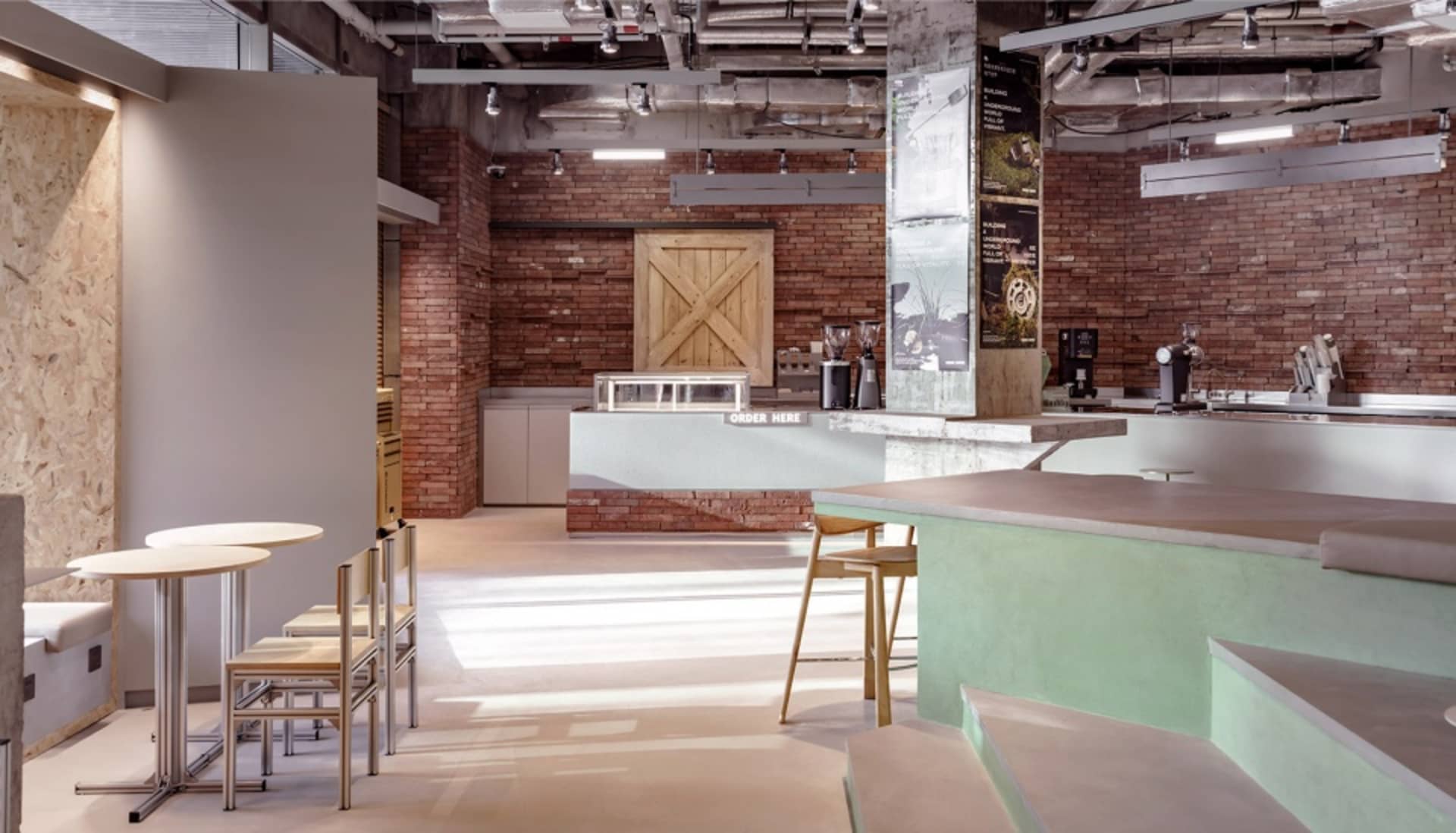 Warm and inviting restaurant interior with a large brick wall, wooden door, and multiple dining tables and chairs