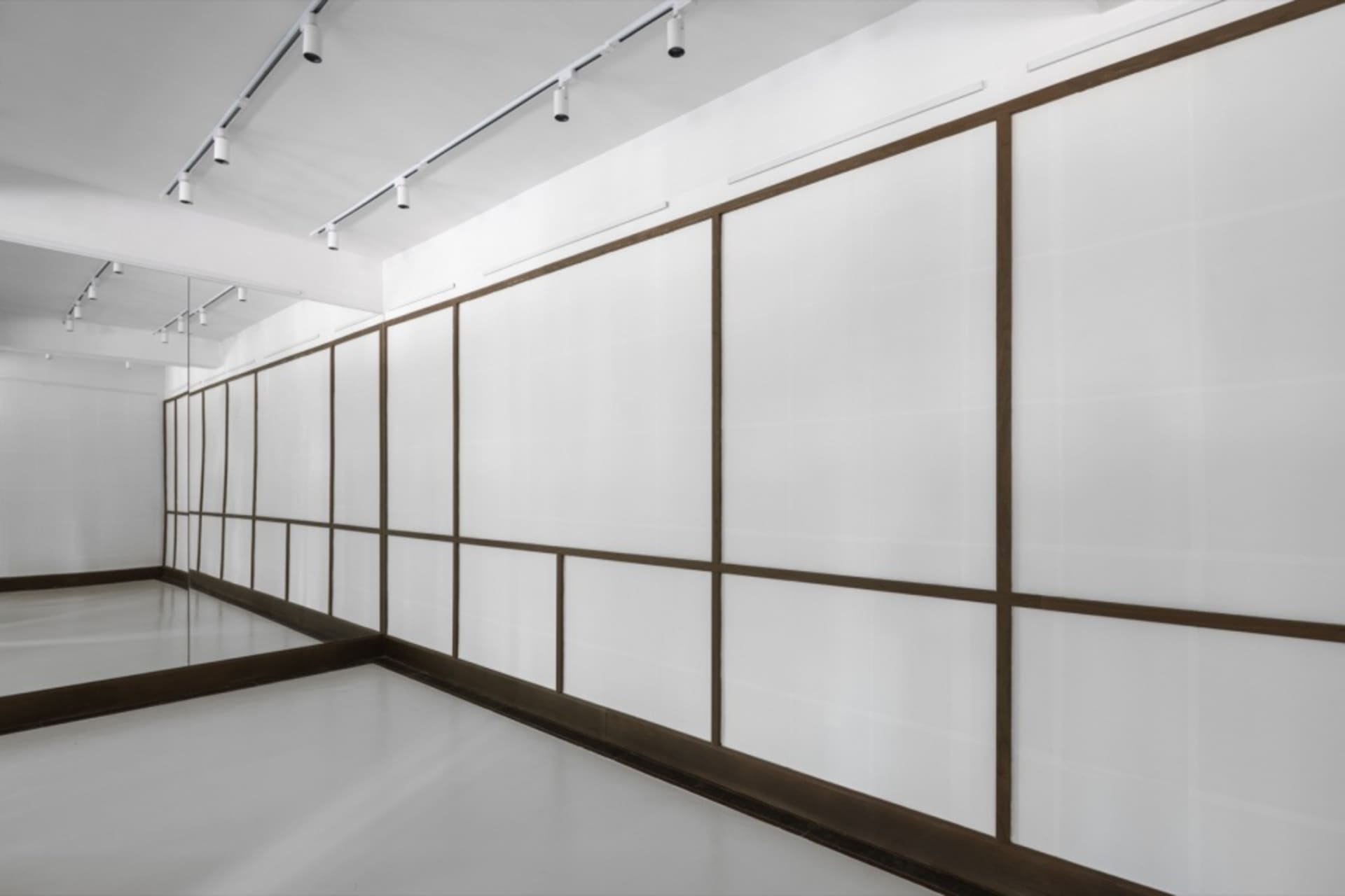 Empty white room with wooden trim and hanging lights, providing a clean and minimalistic atmosphere