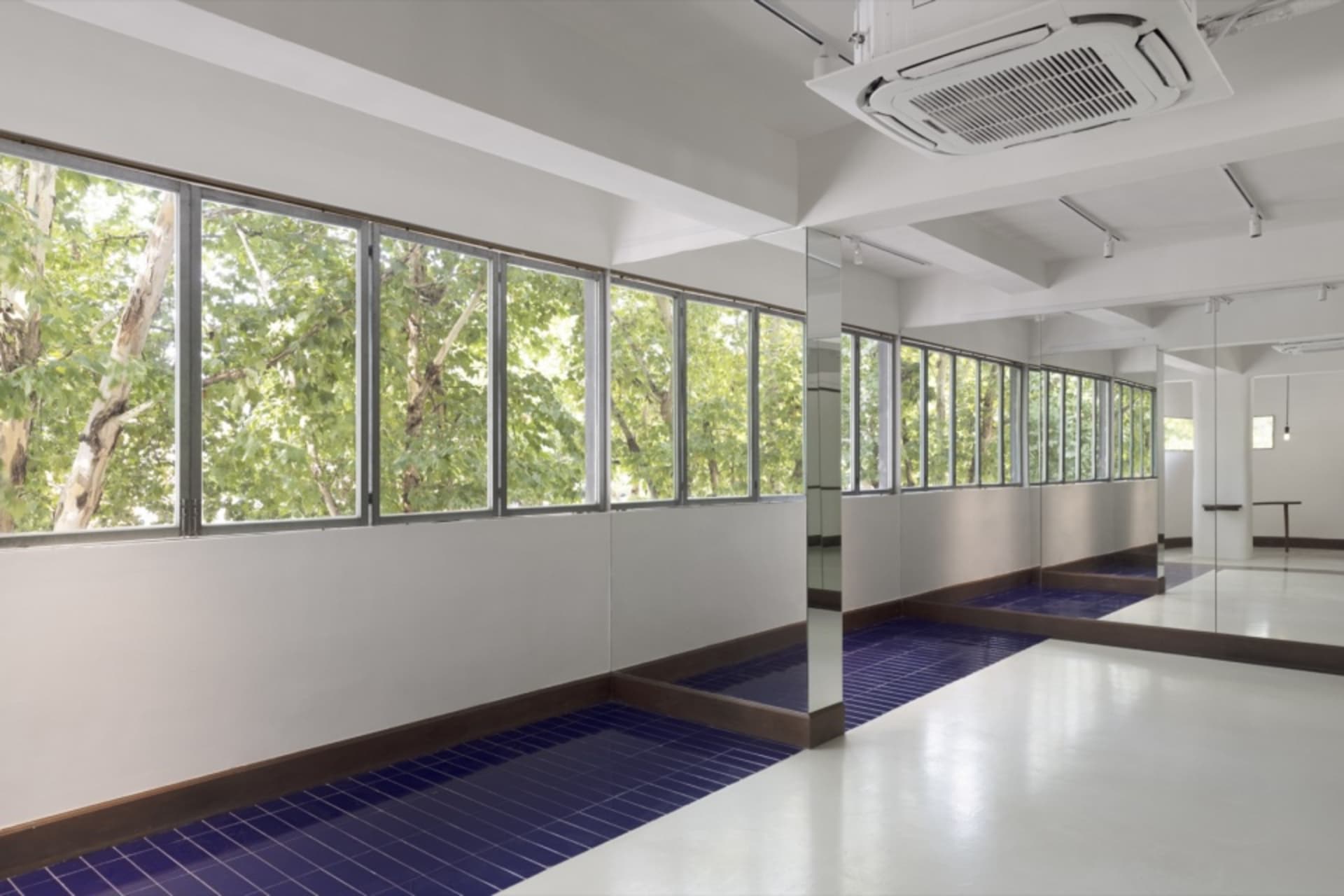 A bright and inviting lobby with natural light pouring in through large windows, offering a view of trees outside, and featuring benches along one wall