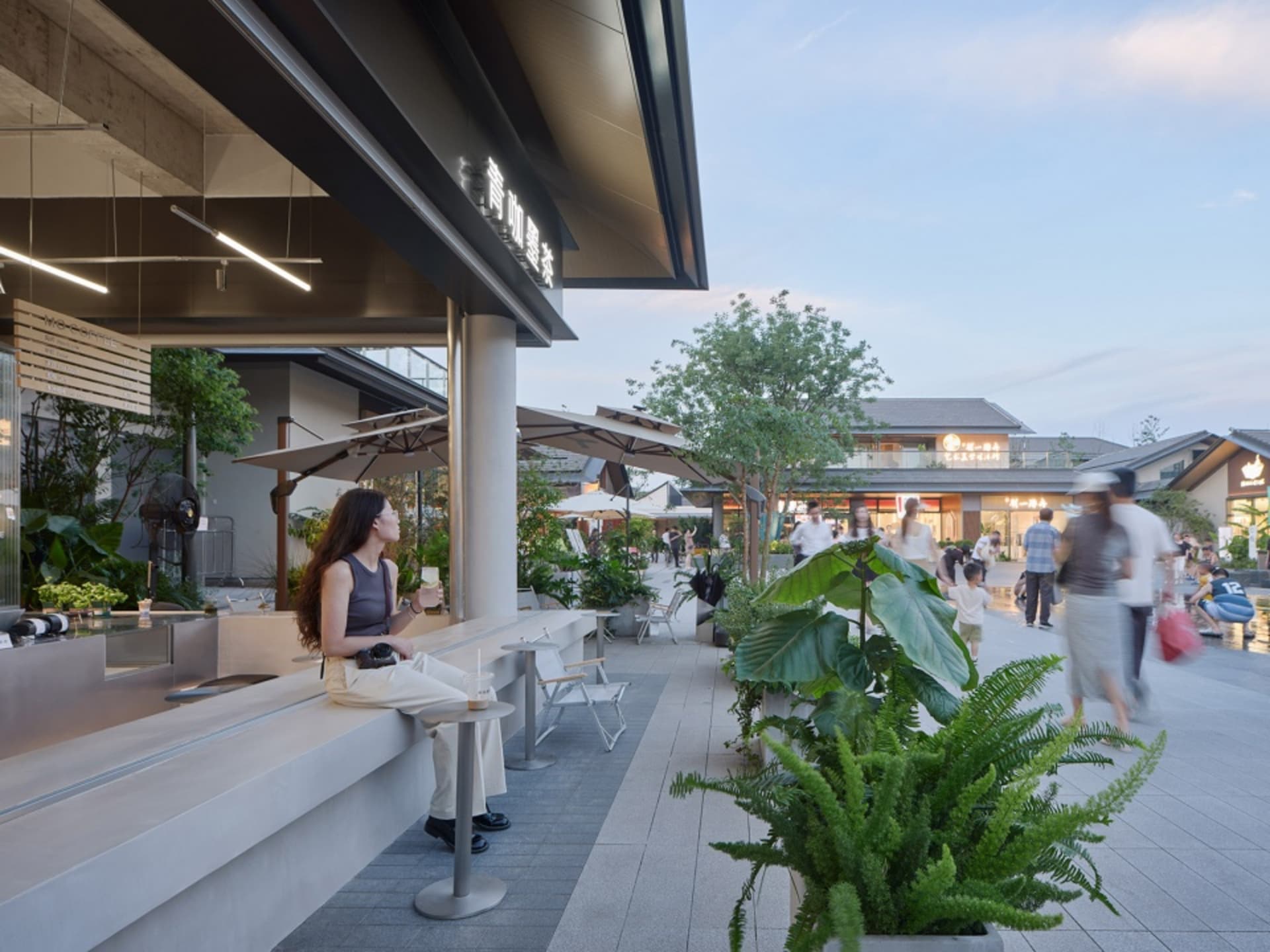 夜晚戶外用餐區，設有桌椅與遮陽傘，人們社交互動，享受歡樂時光