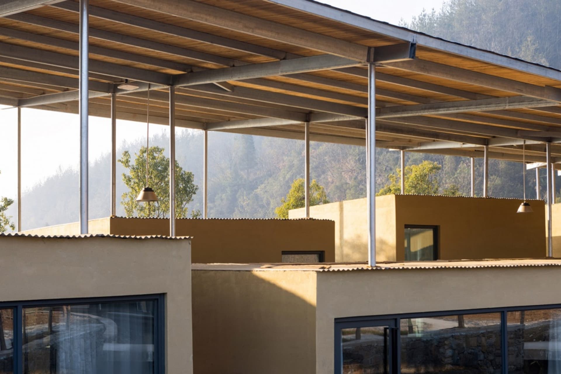 Two wood-sided houses on a hillside surrounded by trees, with natural light coming in through windows, creating a peaceful atmosphere