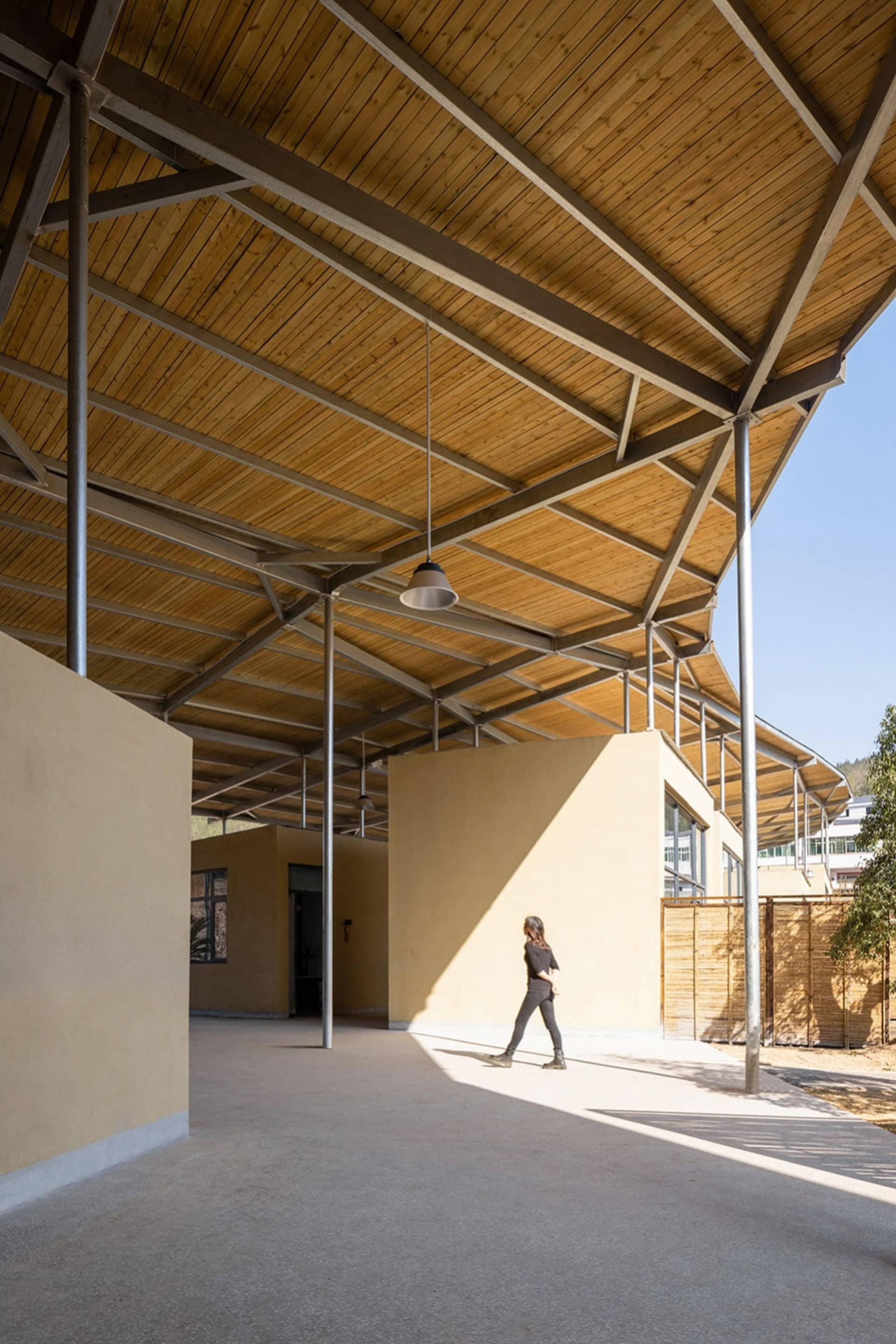 A bright and inviting building with a wooden structure, metal roof, and open area, featuring a mix of wood and metal elements