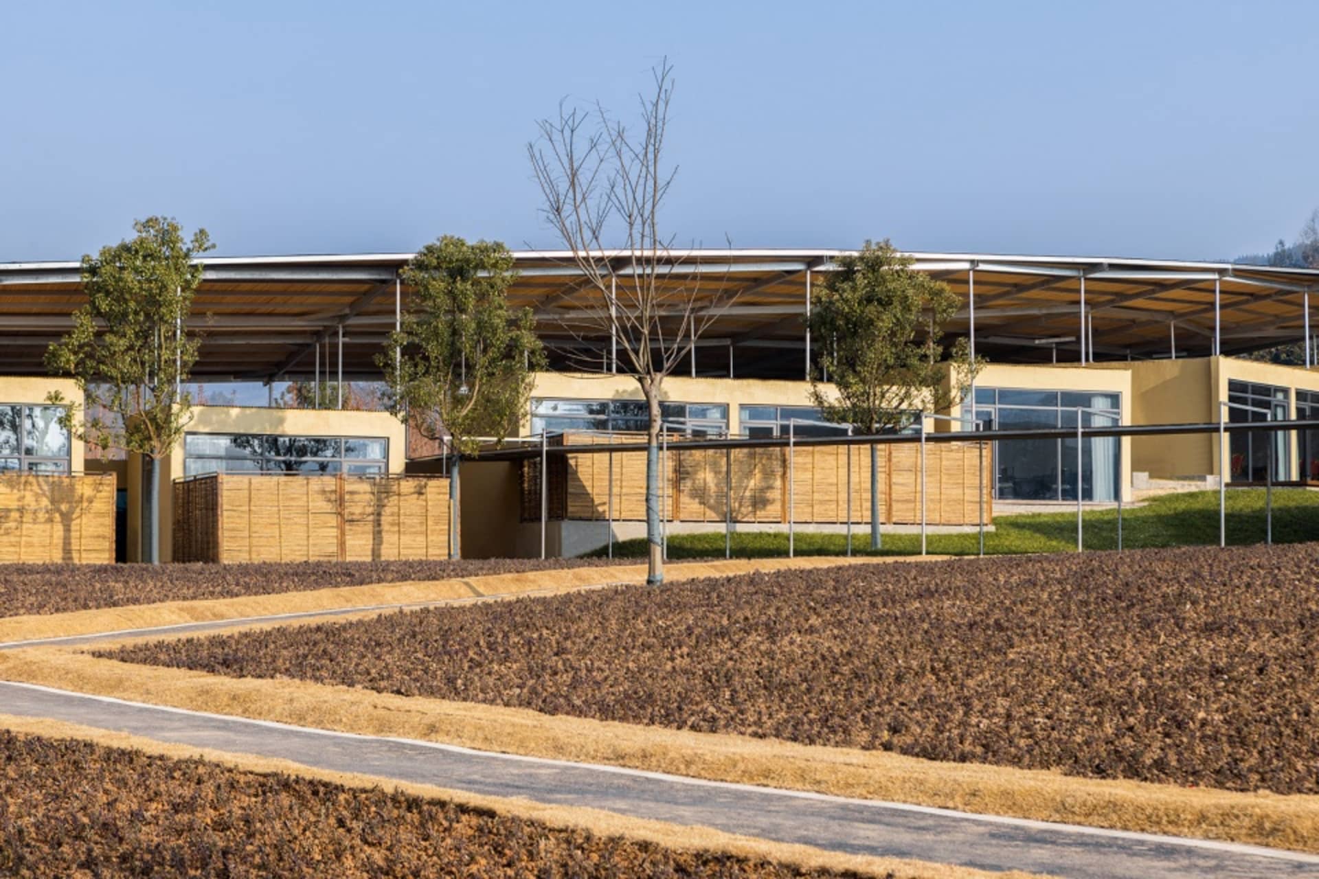 A wooden building with a large open area in front, surrounded by trees and grass, conveying a sense of tranquility and connection to nature