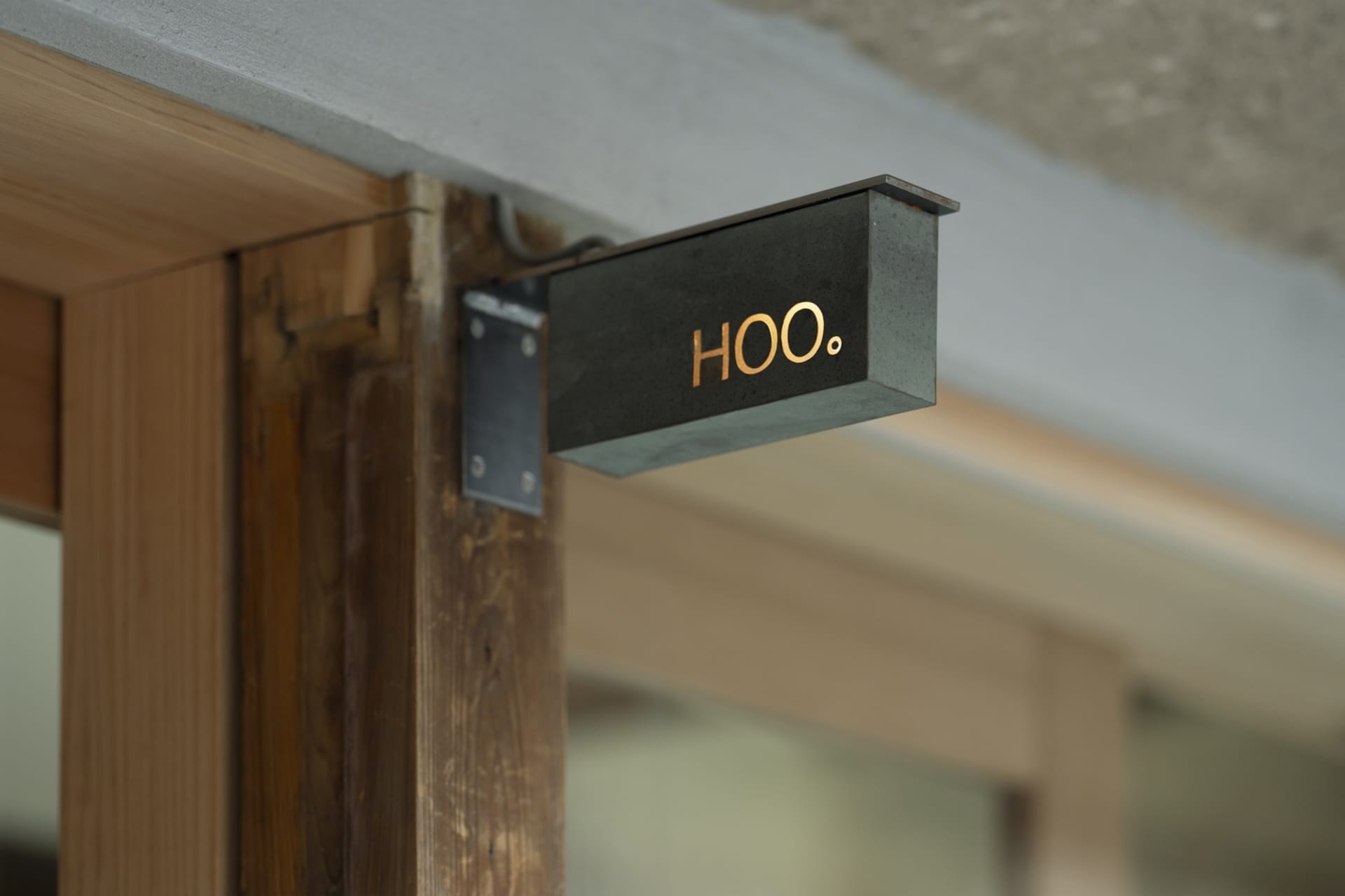 極簡玄關配有木門，門上黑色的「Hoo」招牌，營造溫暖親切的氛圍