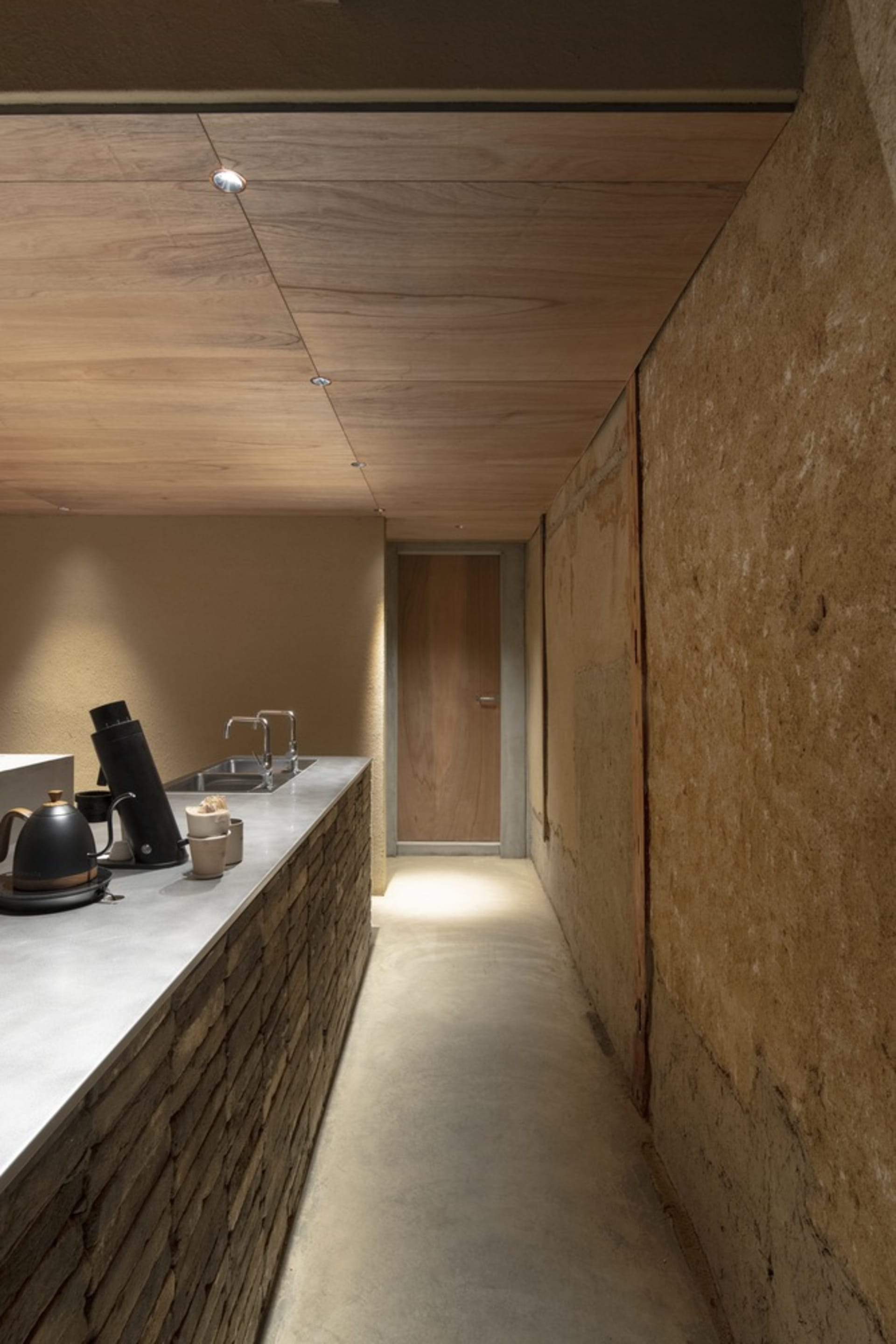 A clean and organized kitchen with two sinks, a countertop with various items, and four bottles scattered around the space