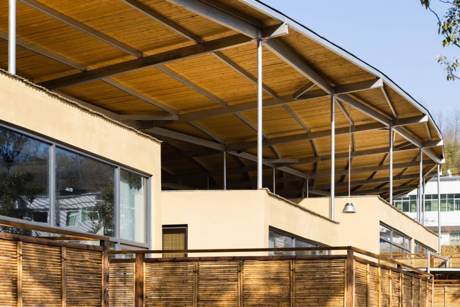 A traditional house with a wooden roof and fence, featuring two windows on the left and three on the right, set against a bright and inviting background