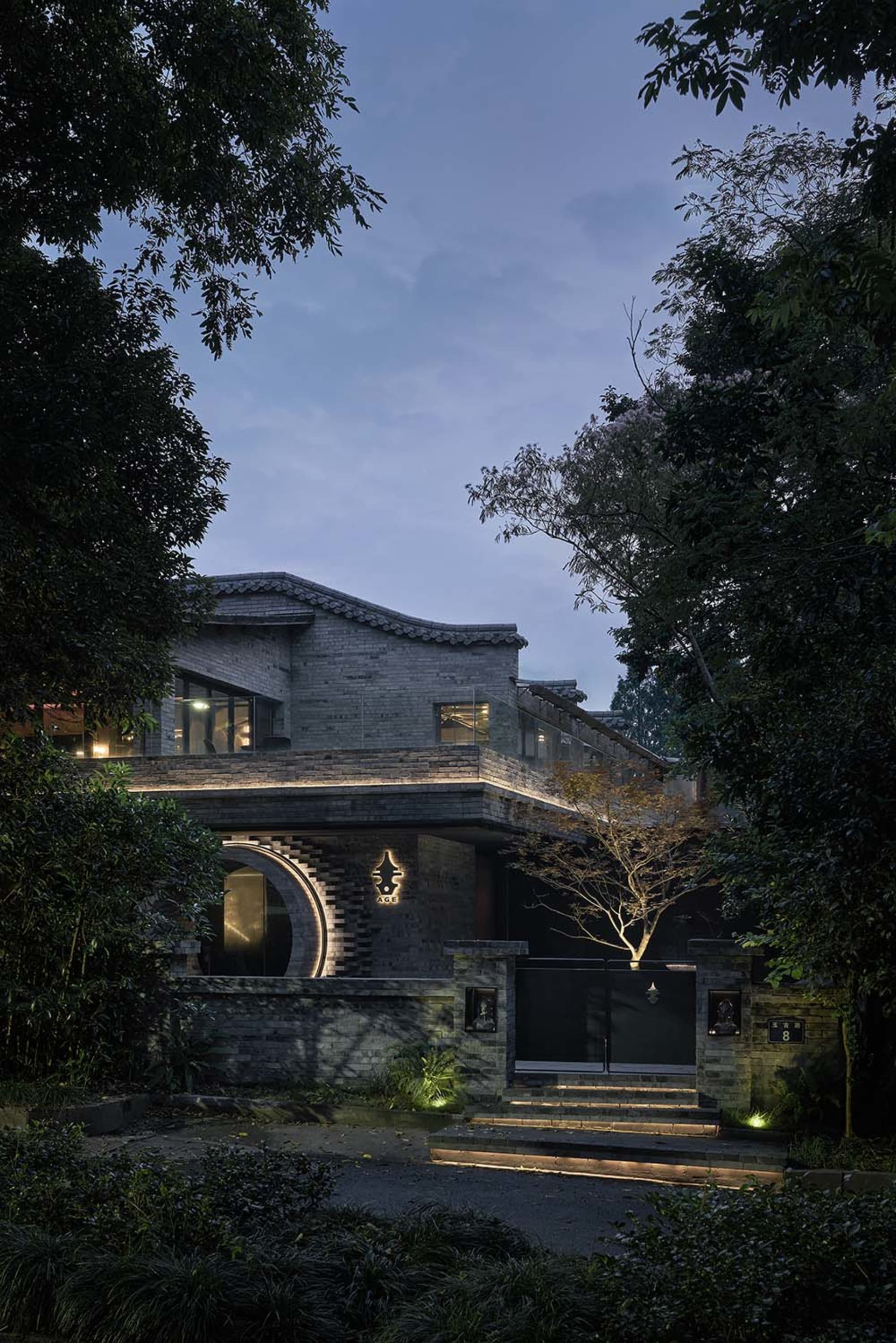 Exterior photo of an Asian-style building with a large stone structure and a courtyard, featuring a blend of traditional and modern elements