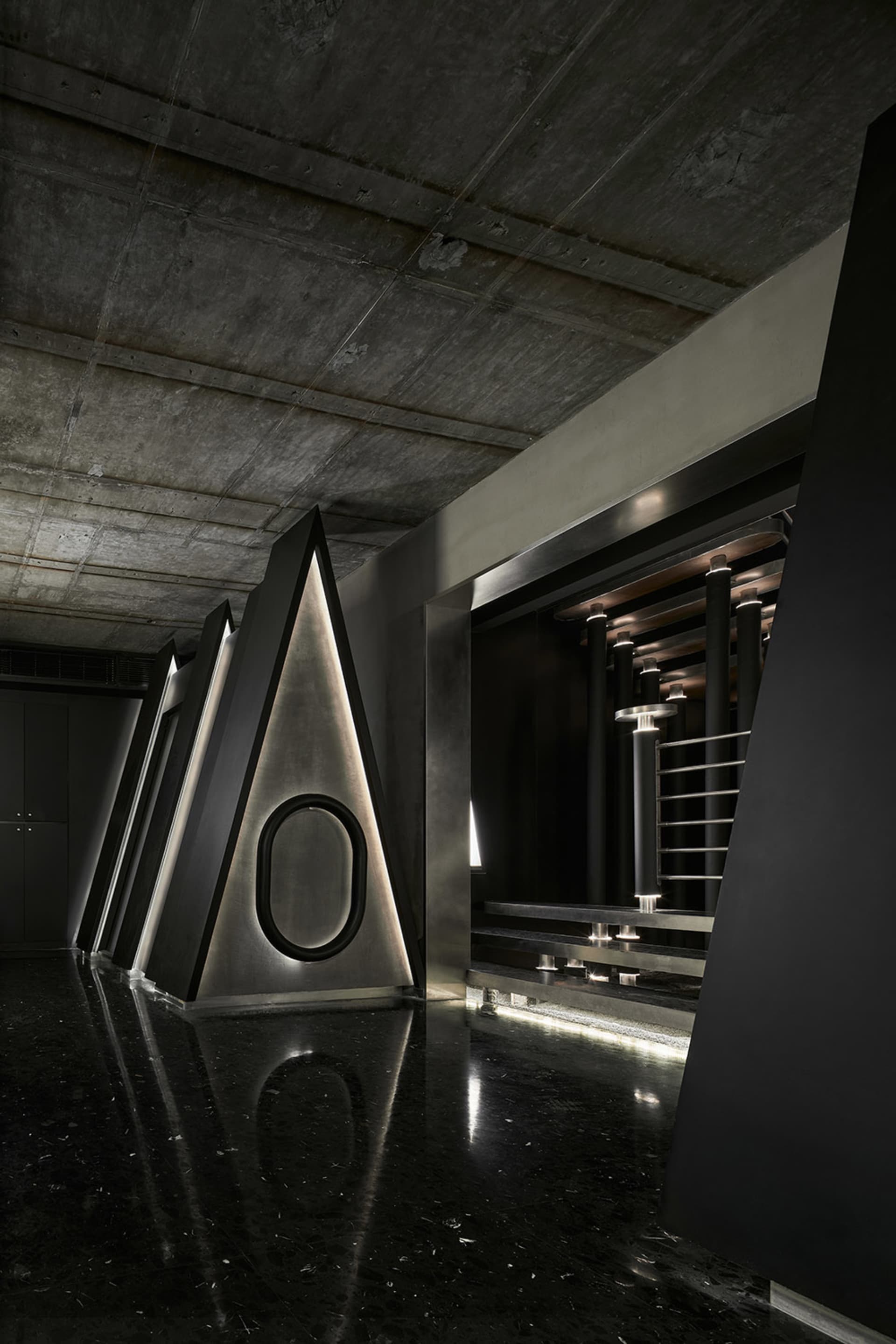 Industrial space with a black and white color scheme, featuring three large metal triangular structures and a minimalist atmosphere