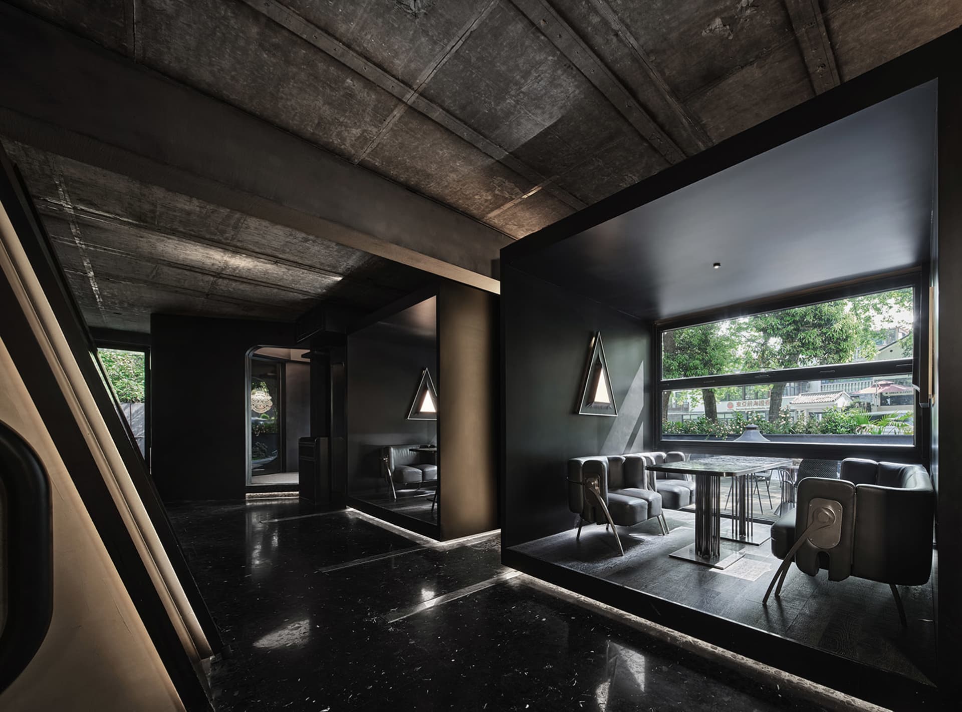 Modern open-plan living space with a black and white color scheme, featuring a dining area, living room, and potted plants, with a sleek and contemporary feel